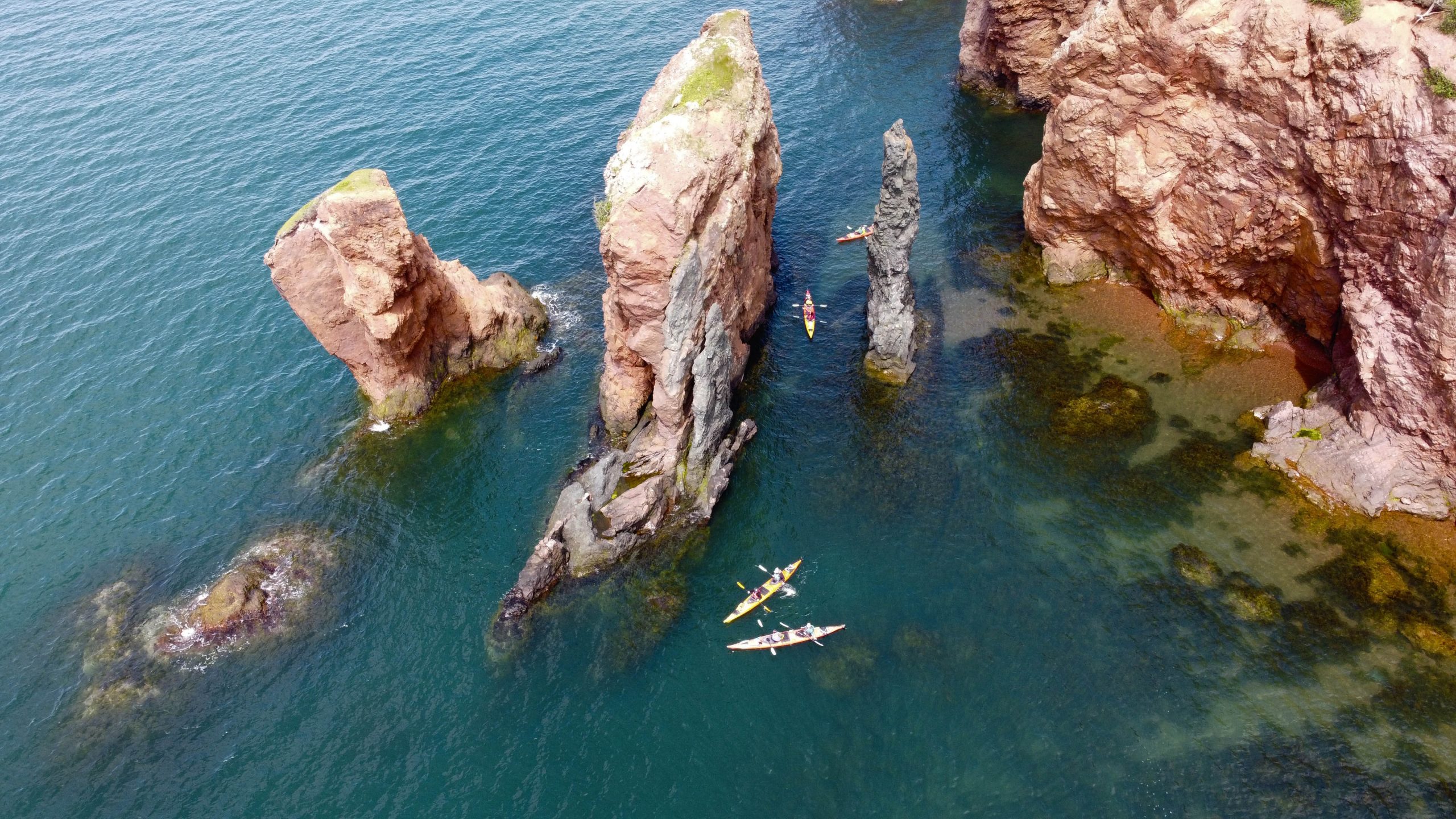 An aerial view of a group of kayakers around the three sisters rock formation with the 3-Day Cape Chignecto Kayak Experience with NovaShores Adventures in Advocate Harbour, Nova Scotia