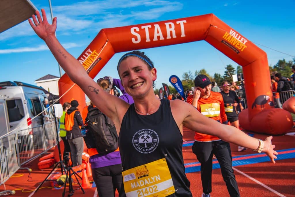 A close up view of a woman crossing the finish line at the Valley Harvest Marathon in Wolfville, Nova Scotia