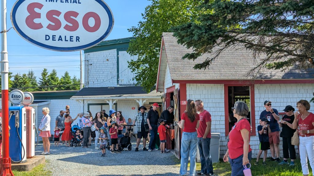 People stands outside in the village during the Dominion Day “Old Time” Village Fair at Memory Lane in Nova Scotia