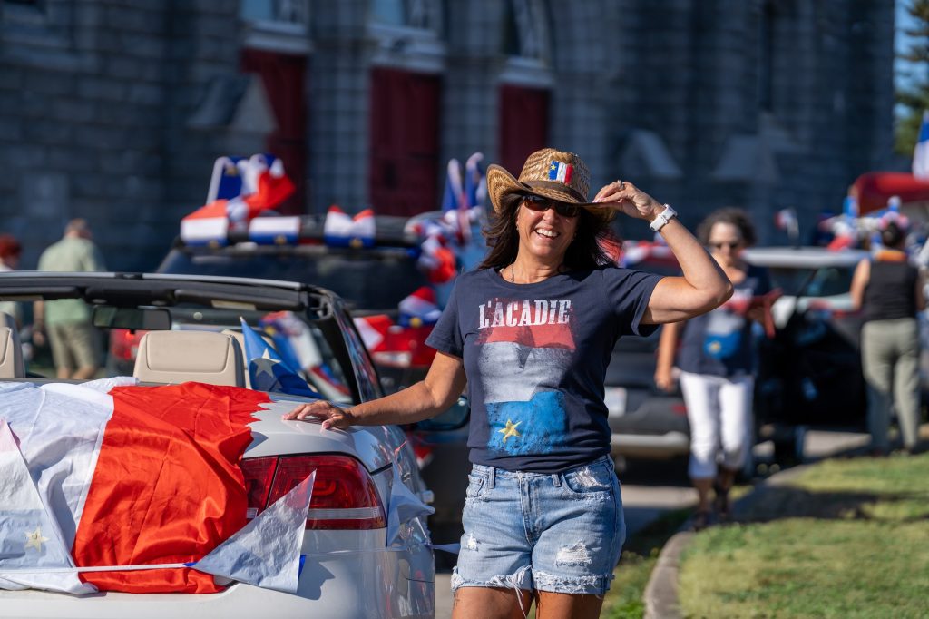 A woman stands next to a car at the Festival acadien de Clare in Nova Scotia