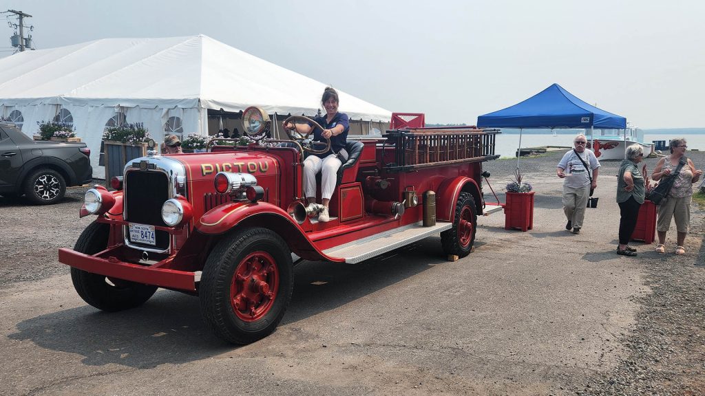 A woman sits on an old fire truck as part of the Pictou Natal Day Celebrations in Nova Scotia
