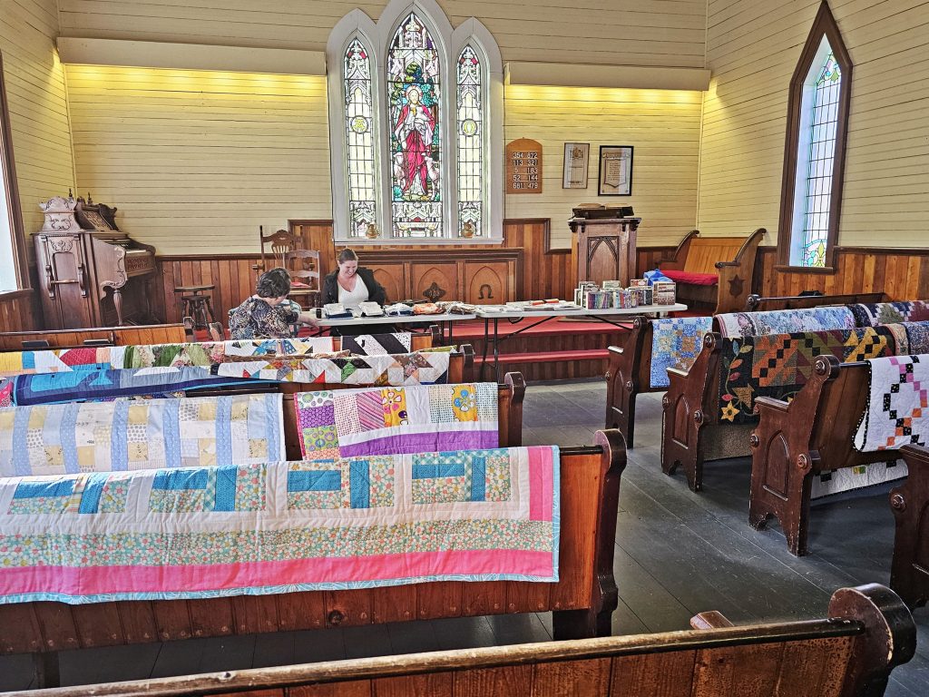 Pews covered in homemade quilts at the Memory Lane Fibre Arts Festival in Nova Scotia