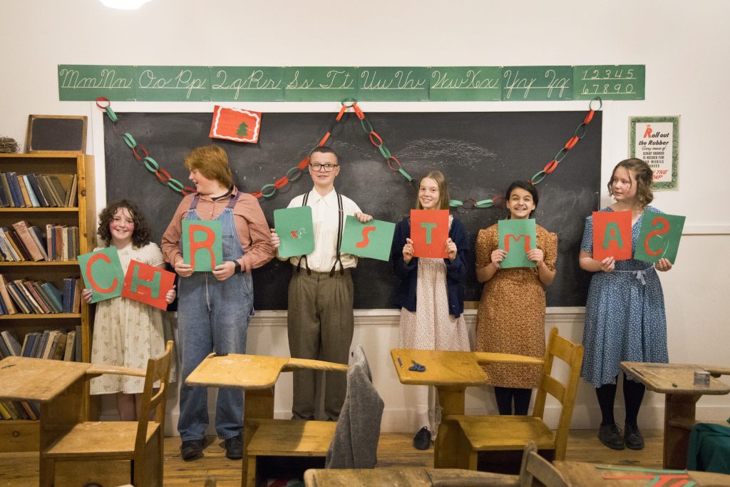 A group of young people hold up a Christmas sign at the Memory Lane Christmas Walk in Nova Scotia