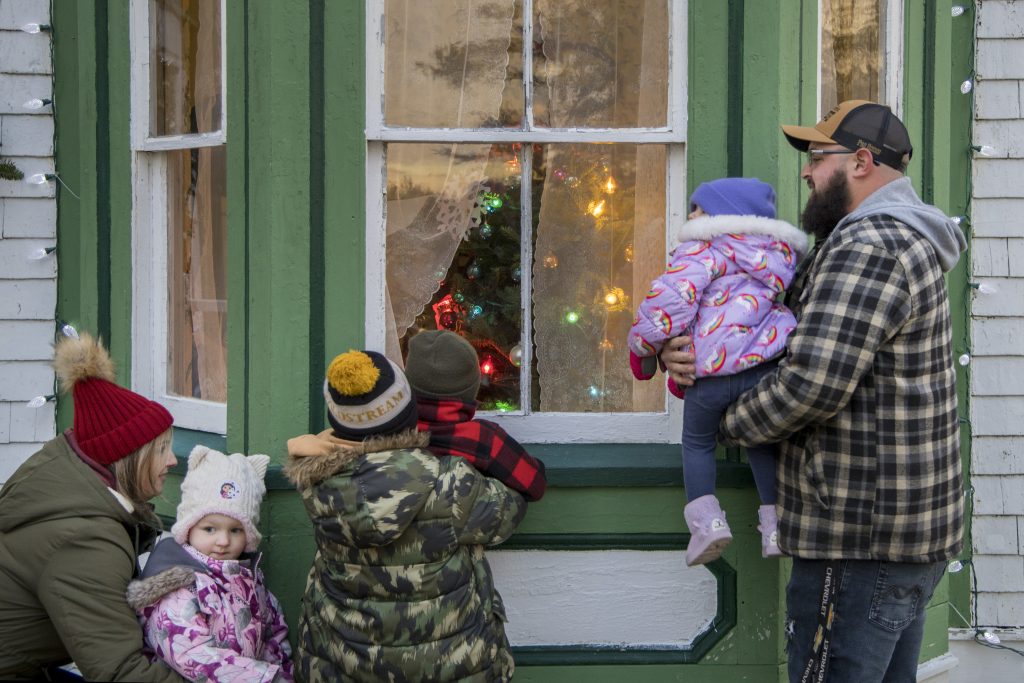A family looks inside a storefront at the Memory Lane Christmas Walk in Nova Scotia