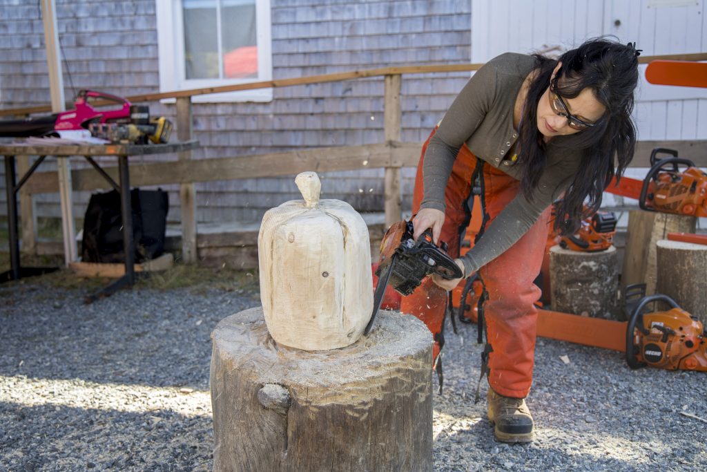 A person carves a wooden pumpkin with a chainsaw during the Nova Scotia Forest Festival at Memory Lane in Nova Scotia