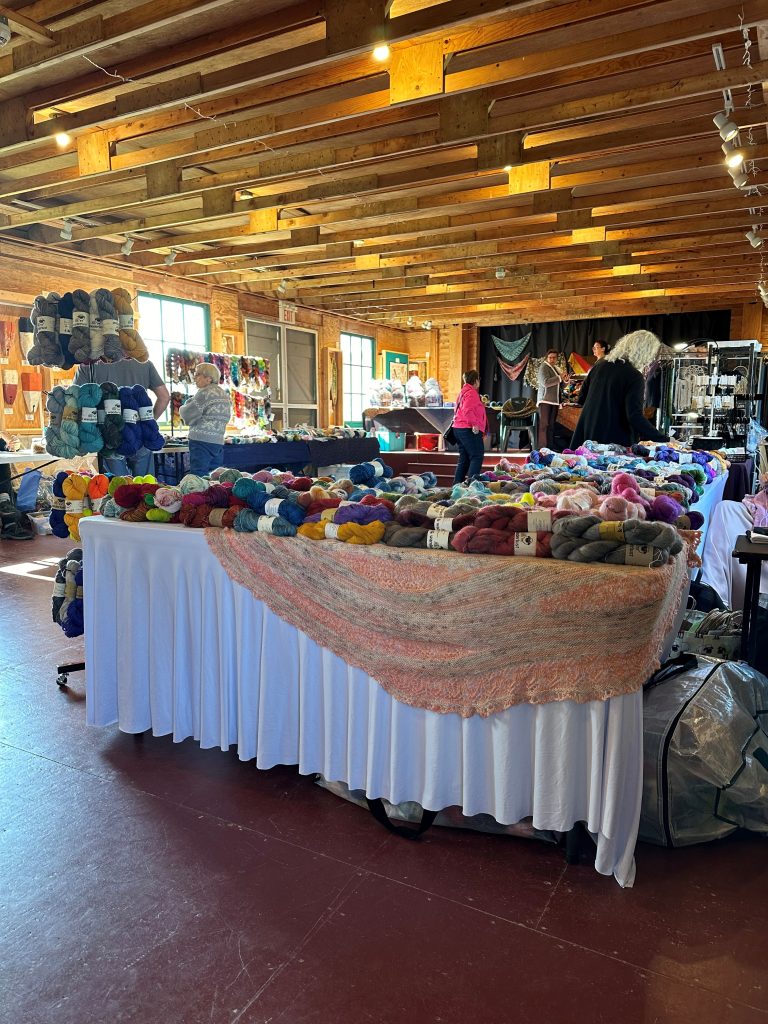 A table full of various yarns and fabric at the Memory Lane Fibre Arts Festival in Nova Scotia