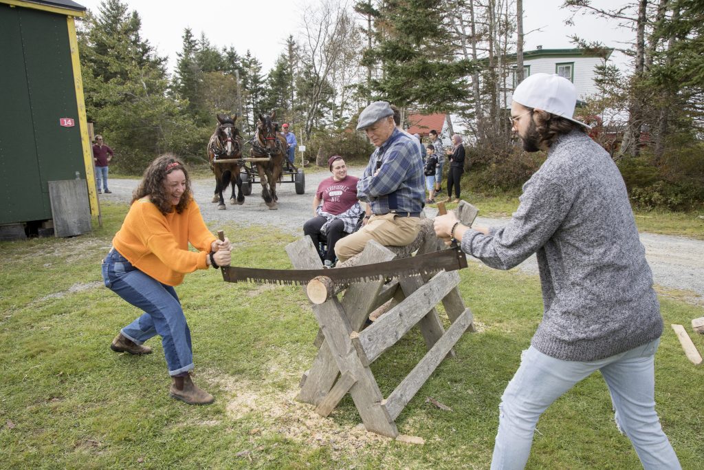 Two people using a long blade saw work together to cut a log at the Nova Scotia Forest Festival at Memory Lane in Nova Scotia