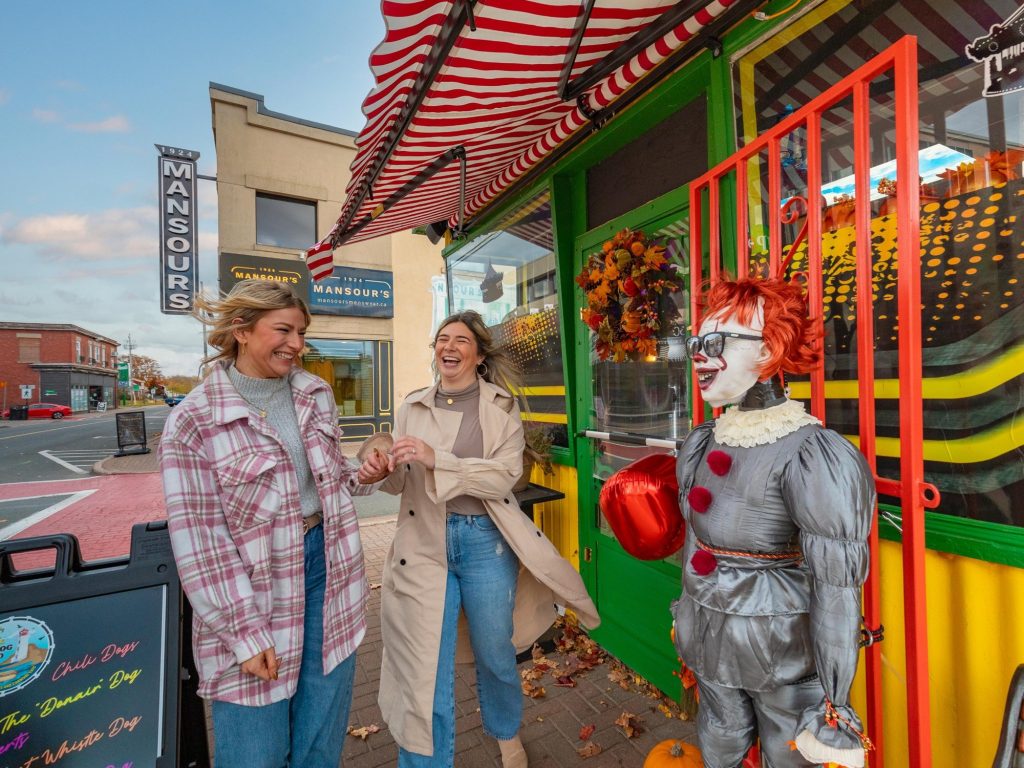 Two women laugh at a scarecrow display during a fall festival in Amherst Nova Scotia