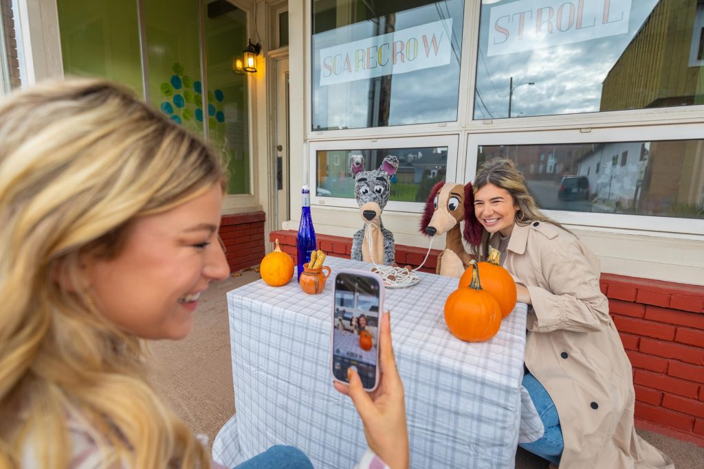 Two women take a photo with a scarecrow display in Amherst, Nova Scotia