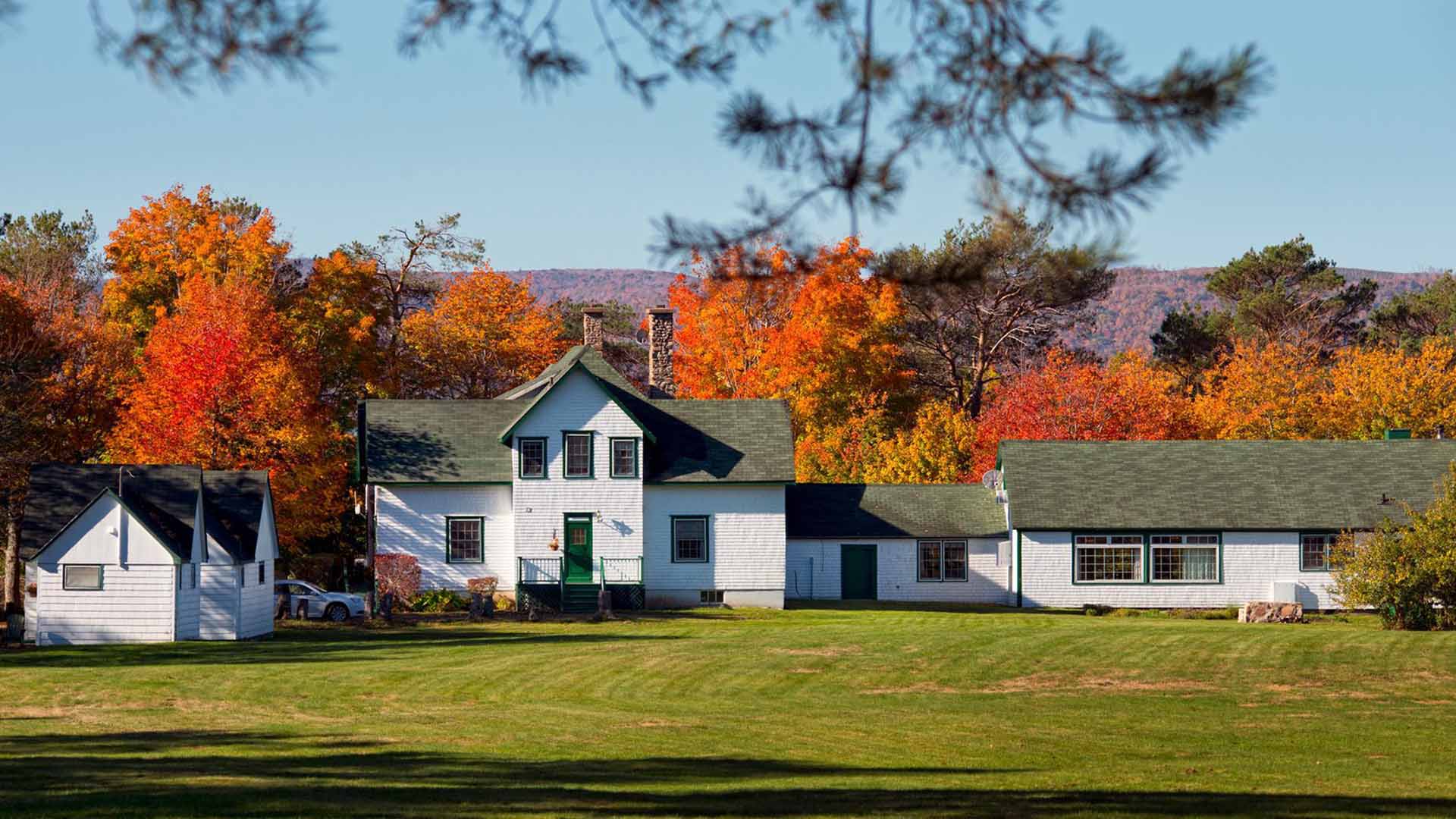 View of part of The Normaway Inn property with the beautiful fall leaf colours in the background in the Margaree Valley in Cape Breton, Nova Scotia