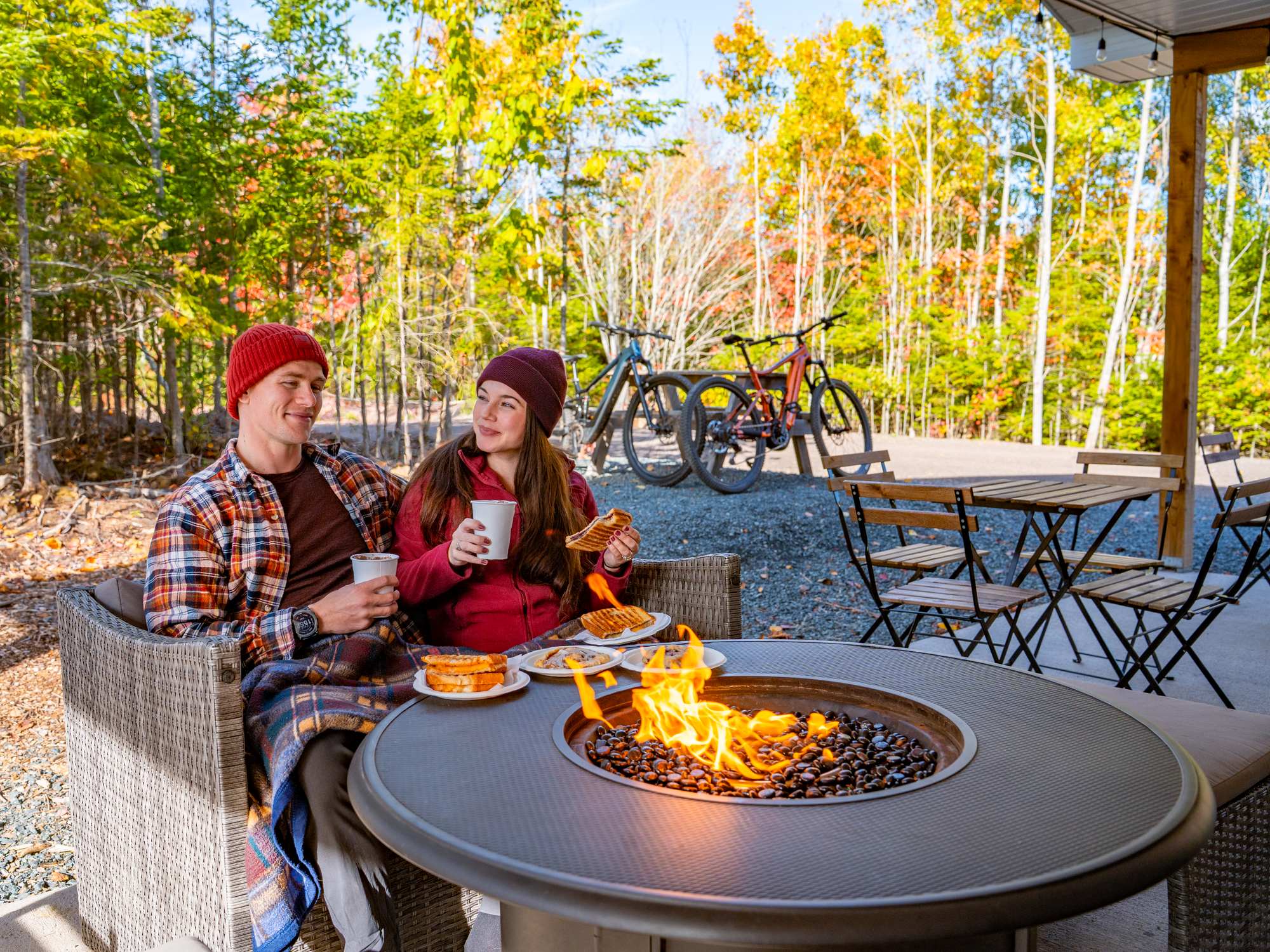 Two people enjoying snacks and beverages around a fire at SEEK