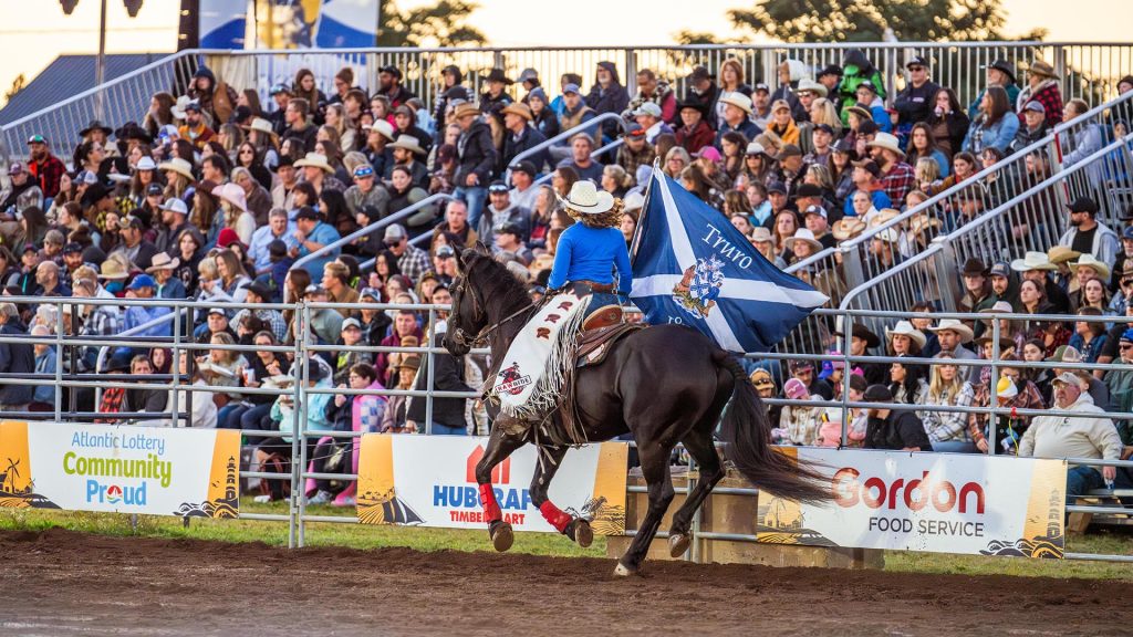 A rider on a horse carries a flag past the crowd during the Nova Scotia Stampede