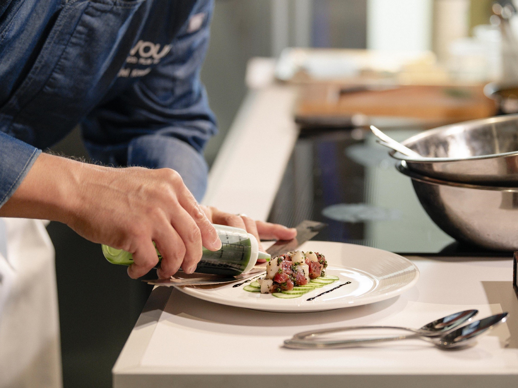 A chef plates a meal and garnishes with a green sauce at Devour The Food Film Festival in Wolfville Nova Scotia