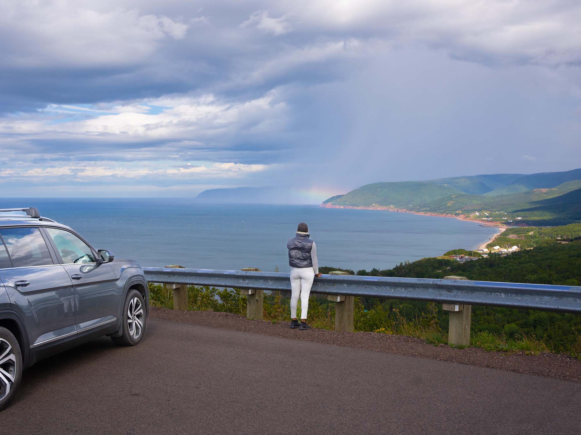 Person taking in the view of a rainbow in the mist from one of the 26 look-offs on the Cabot Trail in Cape Breton, Nova Scotia