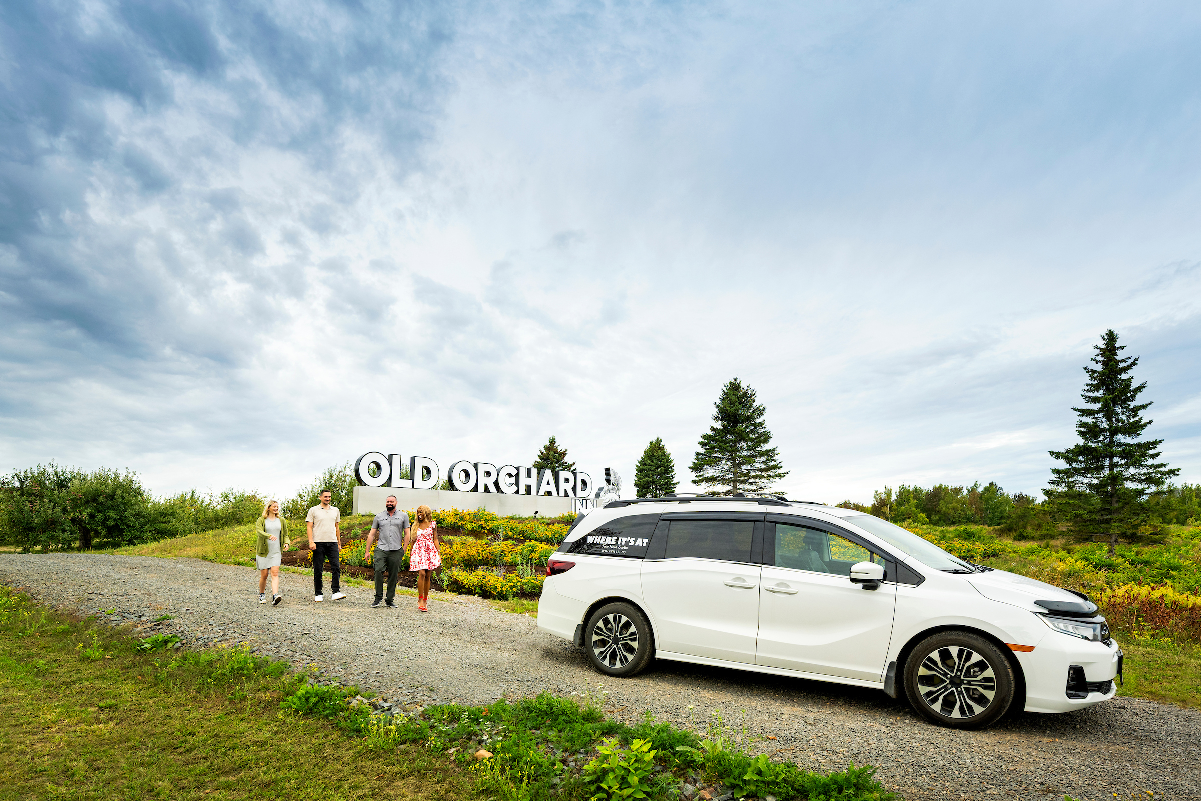 A group walks down a driveway toward a tour vehicle