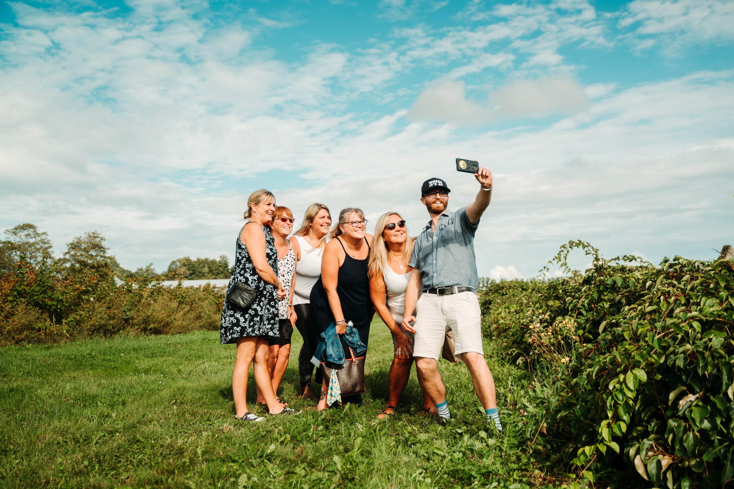 A tour guide takes a selfie with a group of happy looking women in a field