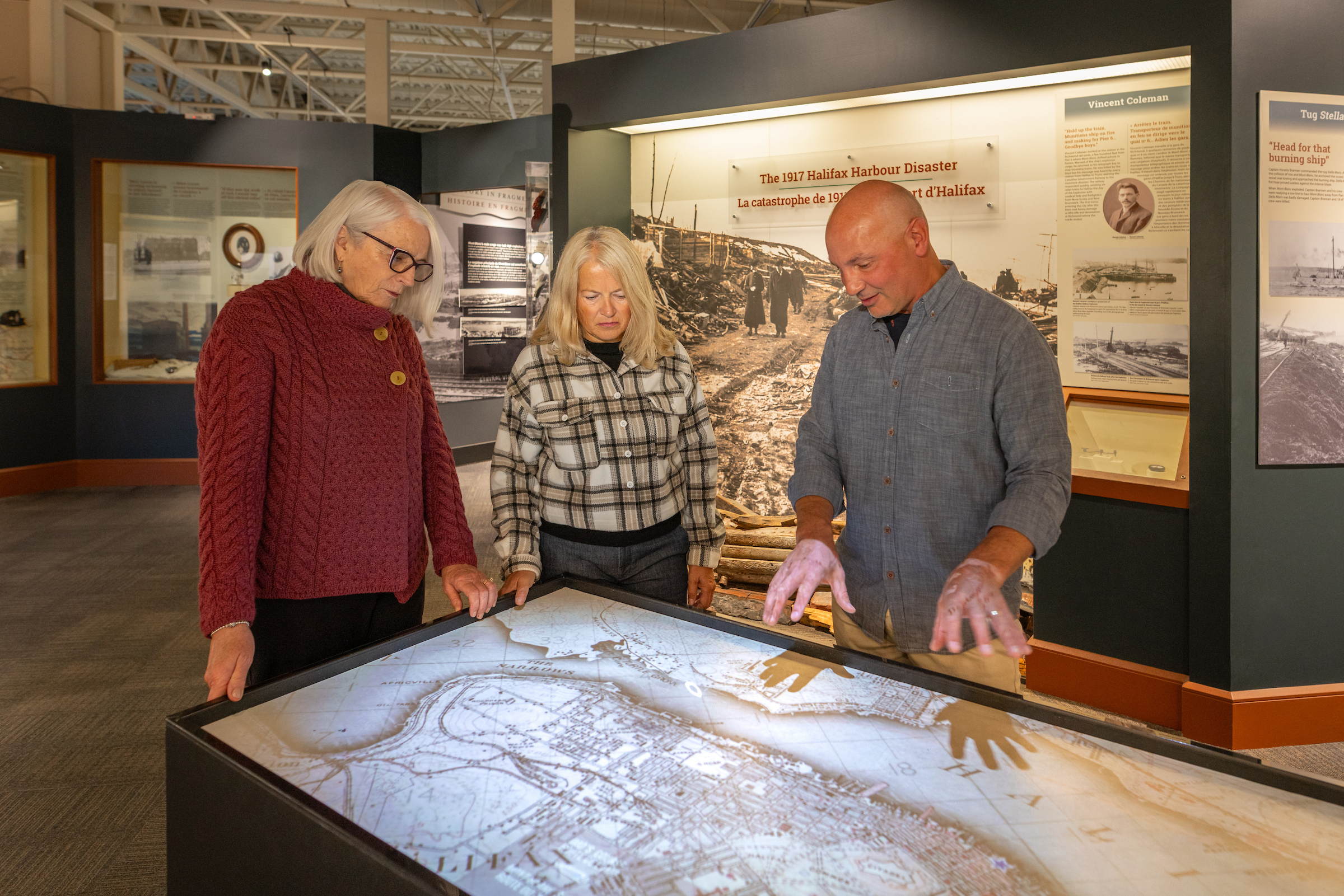 Two women and one man look at an exhibit map of the Halifax peninsula at the Maritime Museum of the Atlantic
