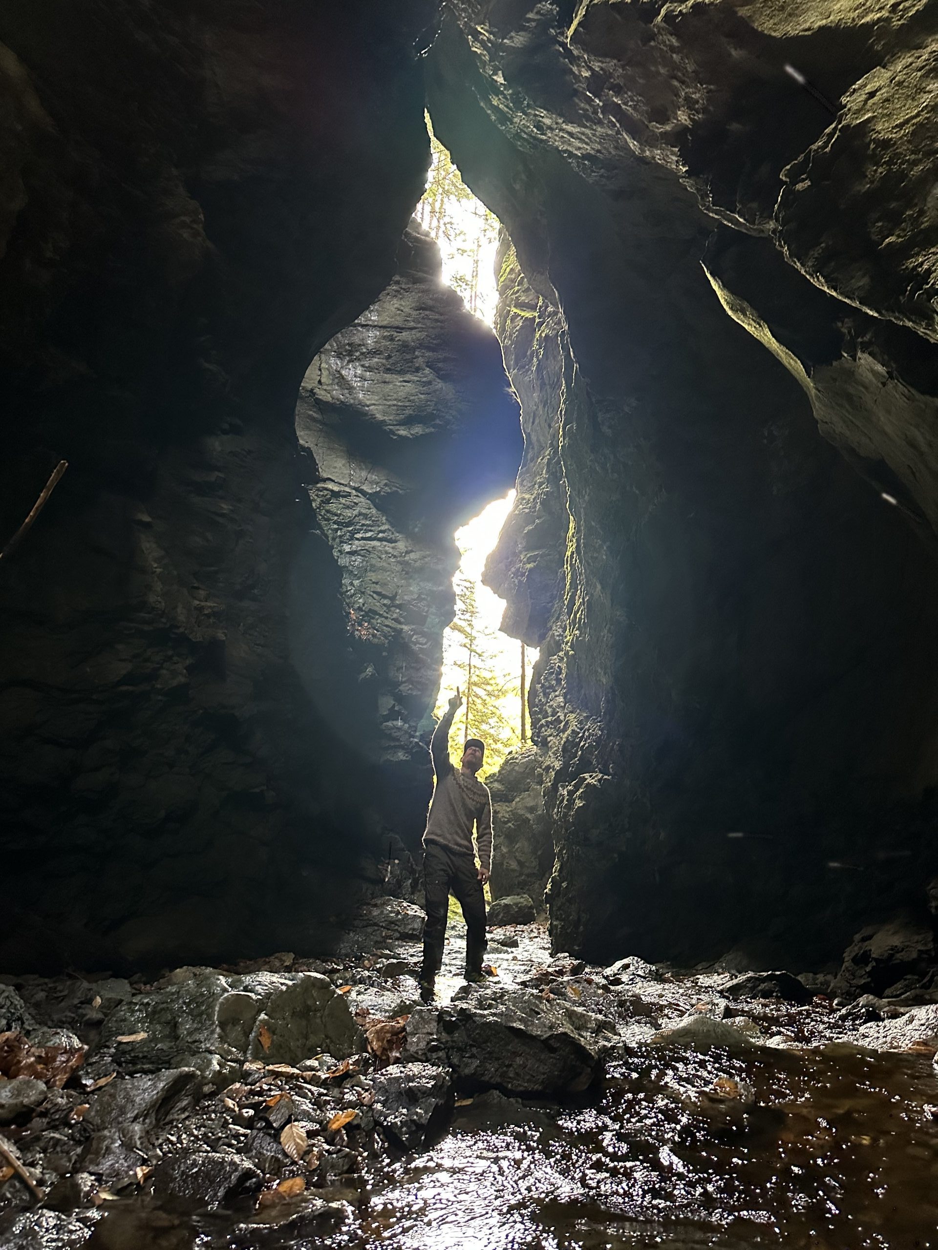Person standing in front of a large split in rock canyon.