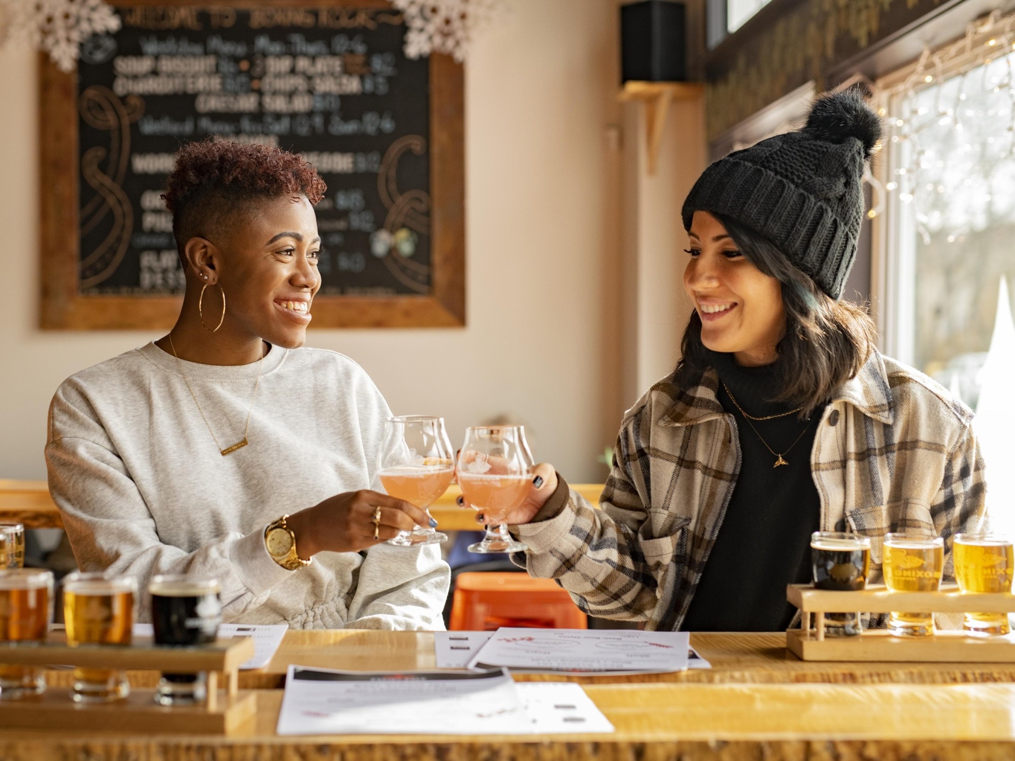 Two women do a cheers with their beer glasses at Boxing Rocking Brewing in Shelburne, Nova Scotia