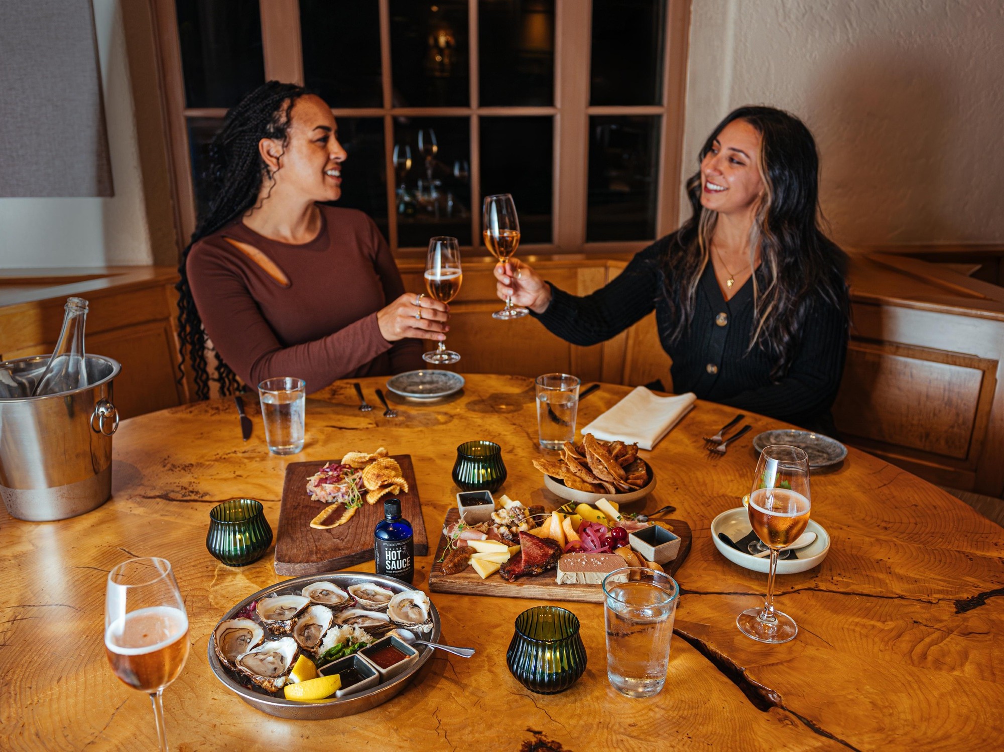 Two women do cheers with their wine glasses as they dine at Le Caveau Restaurant in Nova Scotia.