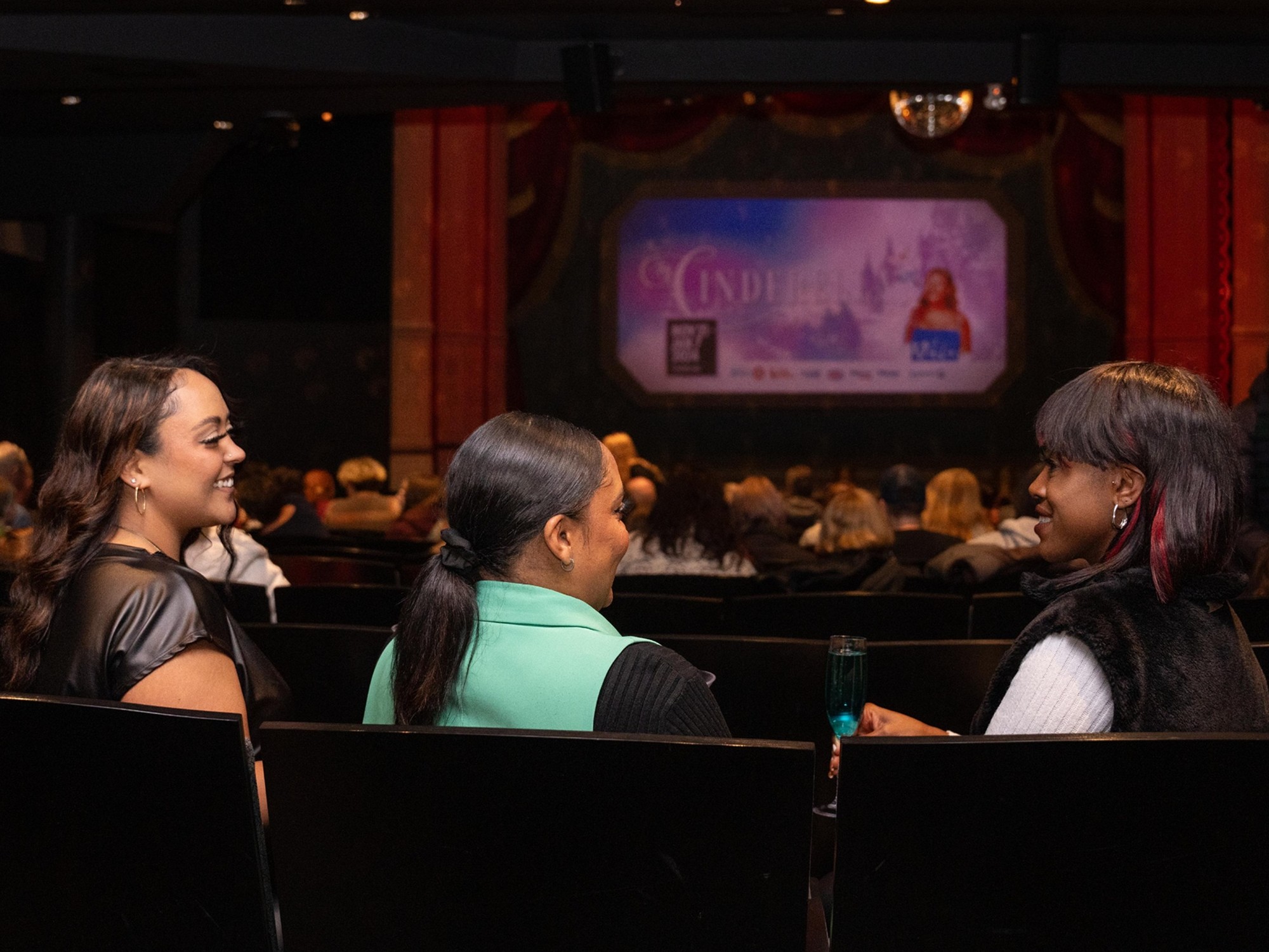 Three women sit in the audience at Neptune Theatre in Halifax, Nova Scotia.