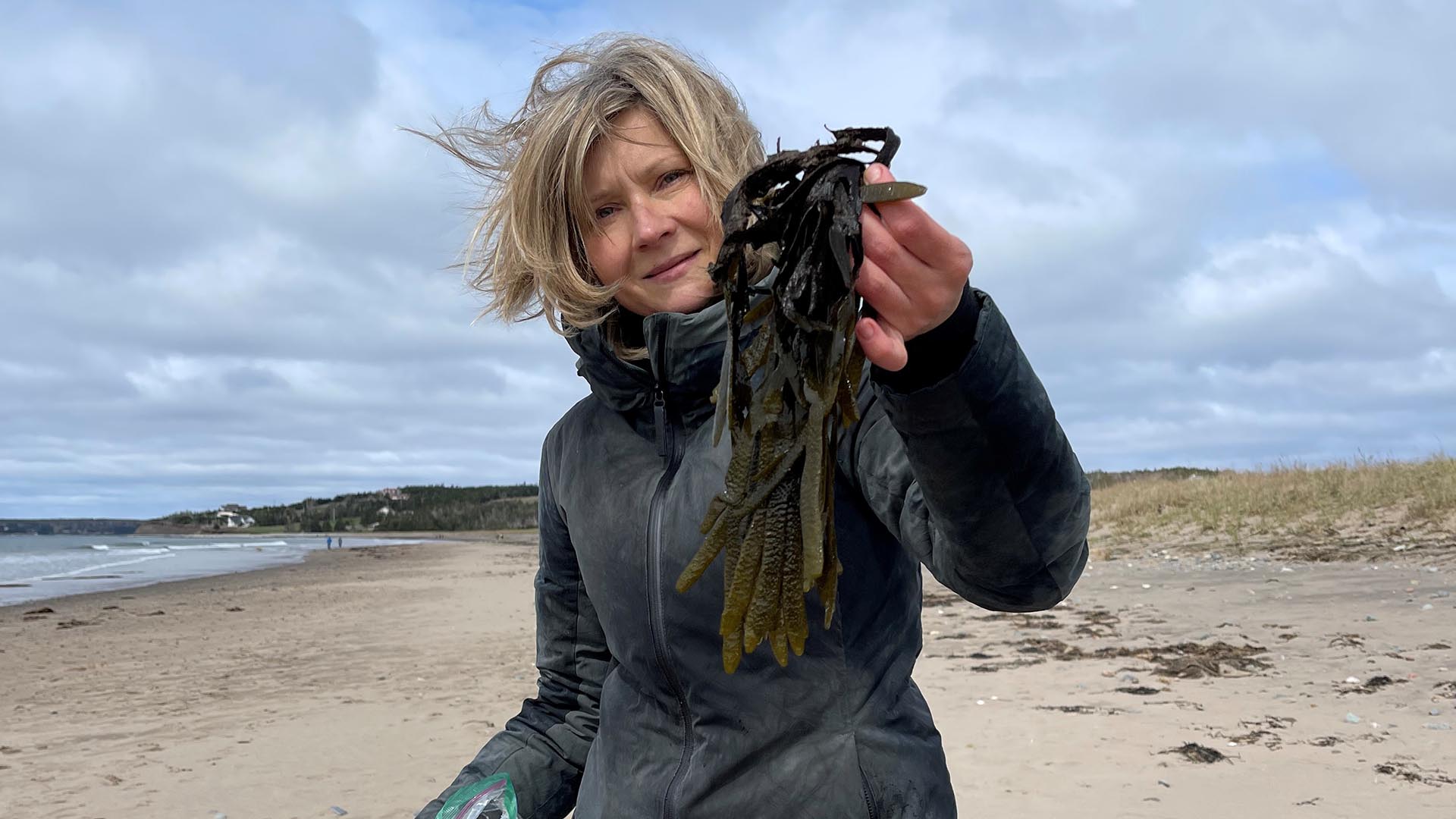 Jolanta from Terroir and Wild Ecotours holds up some seaweed while standing on a beach