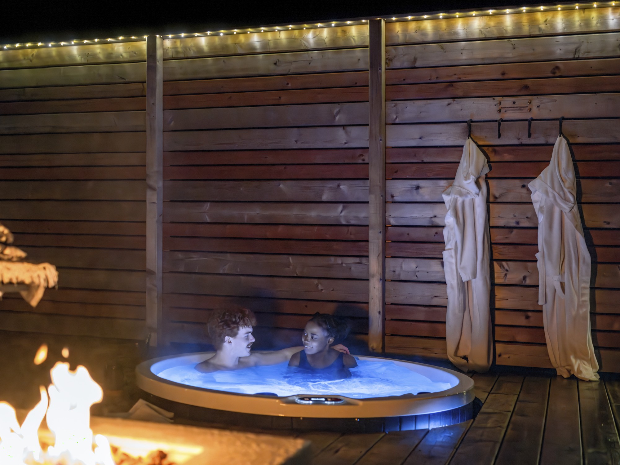 Two people relax in a hot tub at night at Nalu Retreat in Nova Scotia