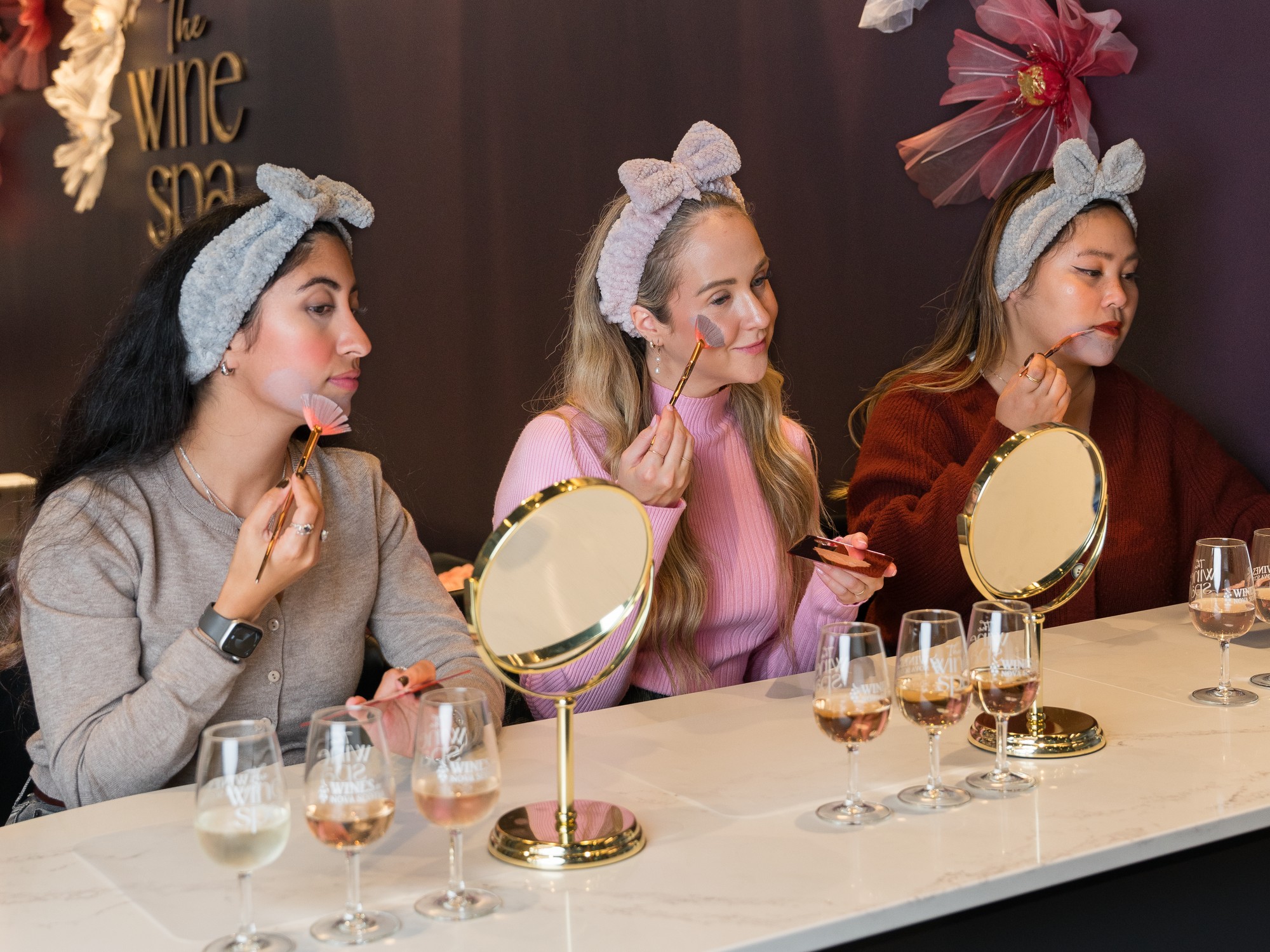 Three women apply face masks at the Wine Spa in Halifax, Nova Scotia