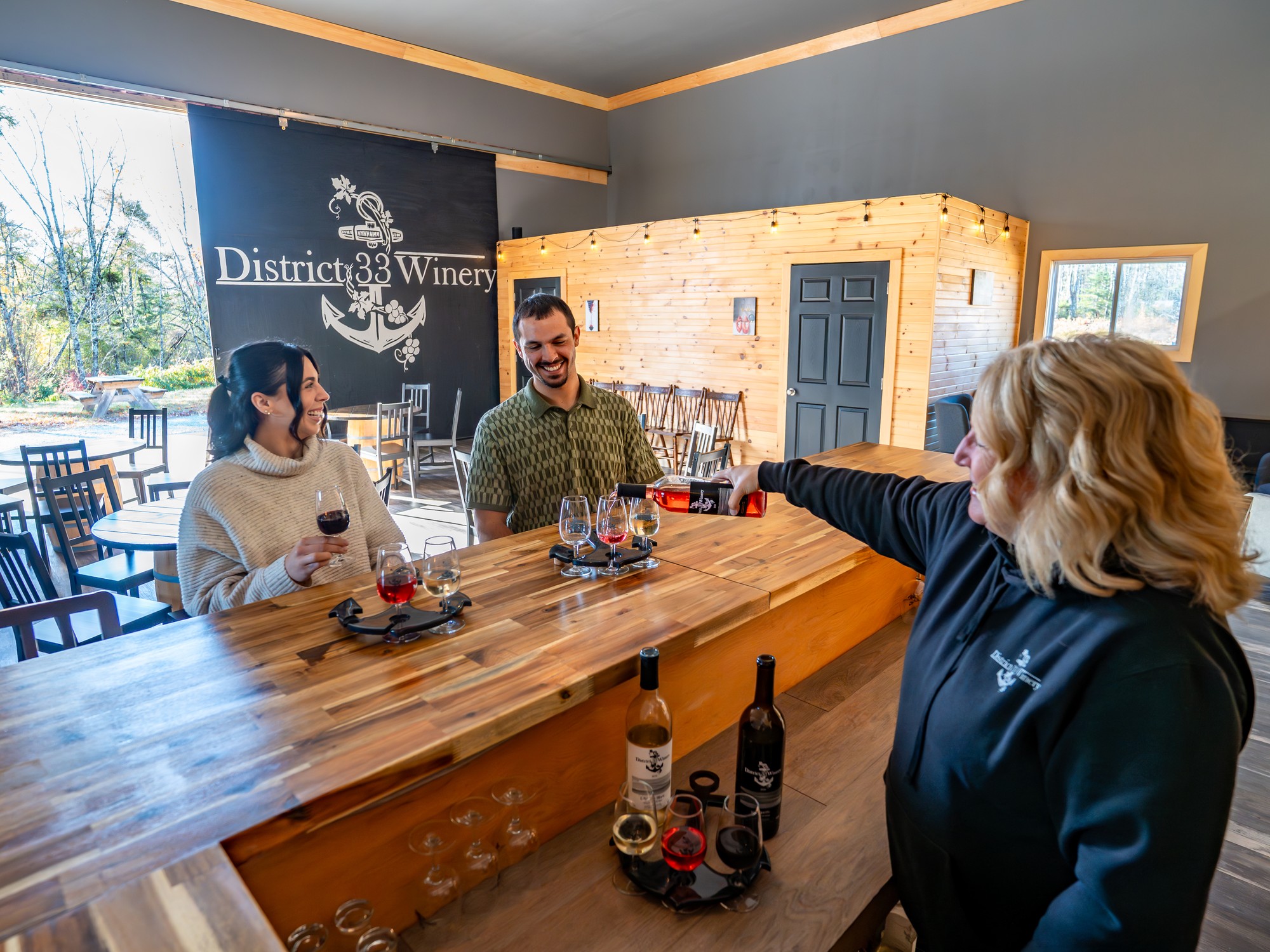 Two people are served glasses of wine at District 33 Winery in Shelburne, Nova Scotia