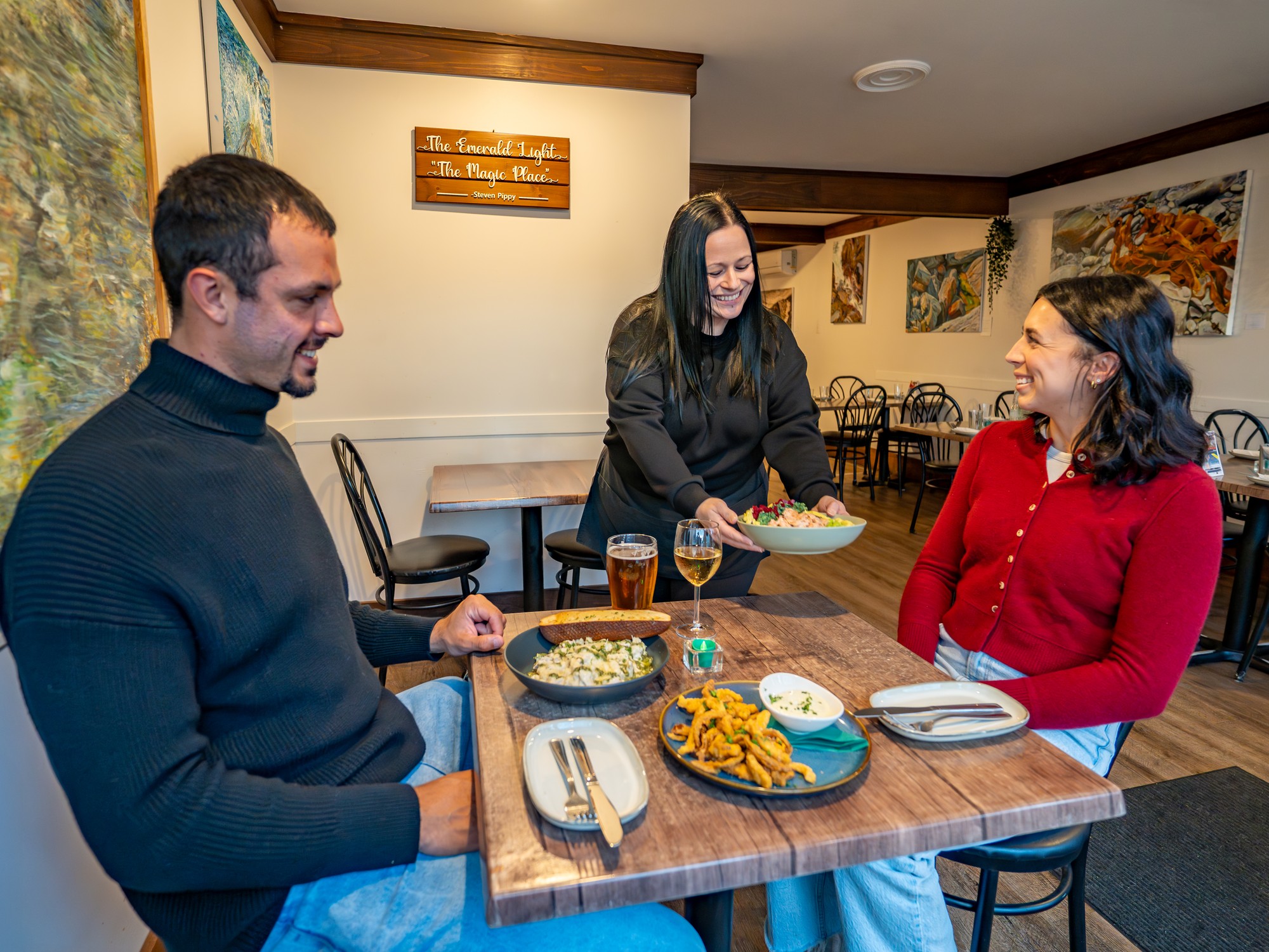 A server brings two diners food at The Emerald Light Kitchen in Shelburne, Nova Scotia