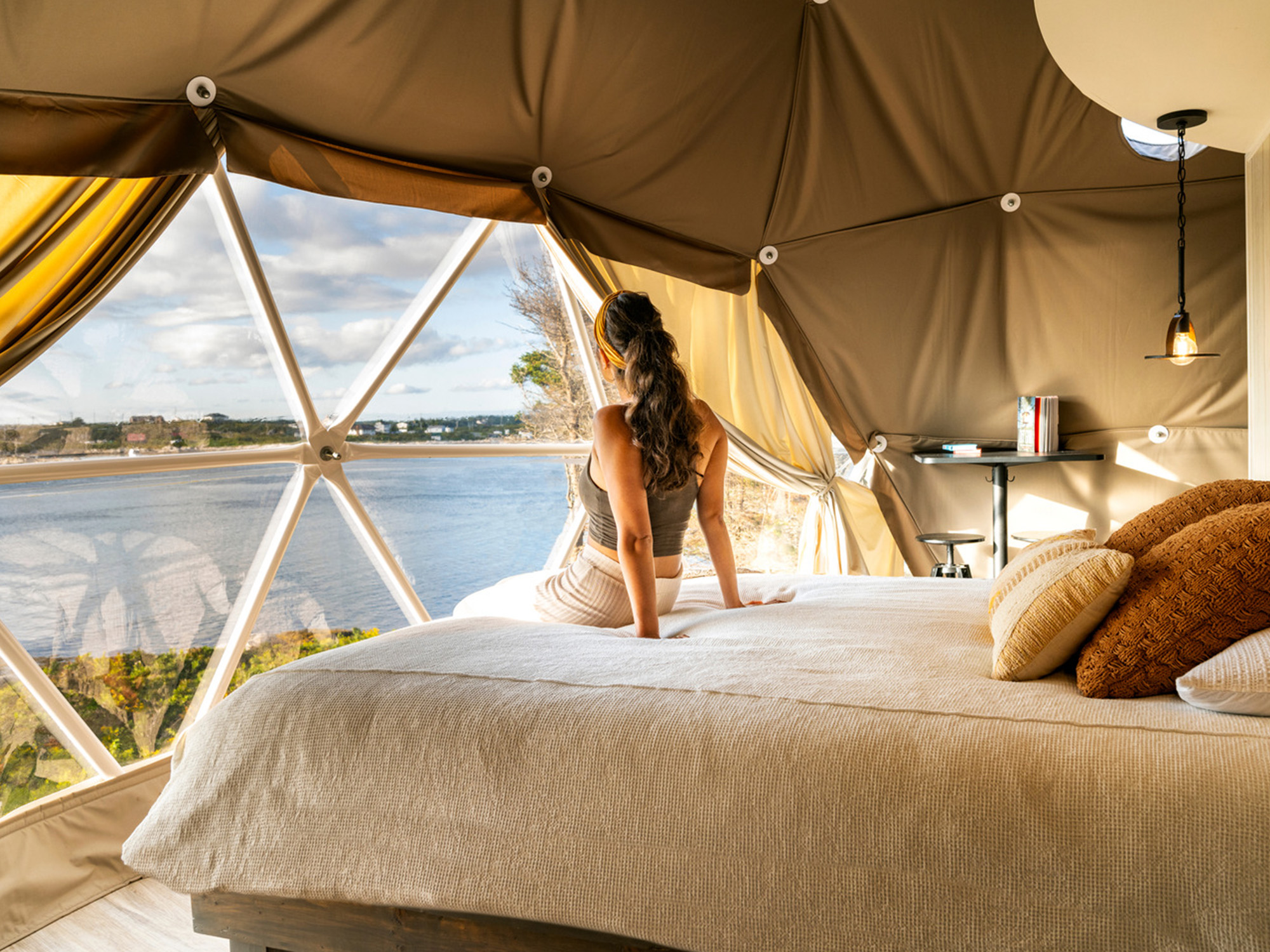 A women sitting on a bed looking out the window at Nova Glamping in West Dover