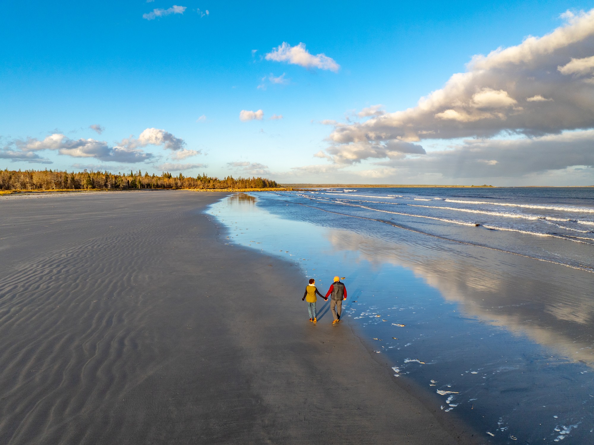Two people walk along Roseway Beach in Shelburne, Nova Scotia