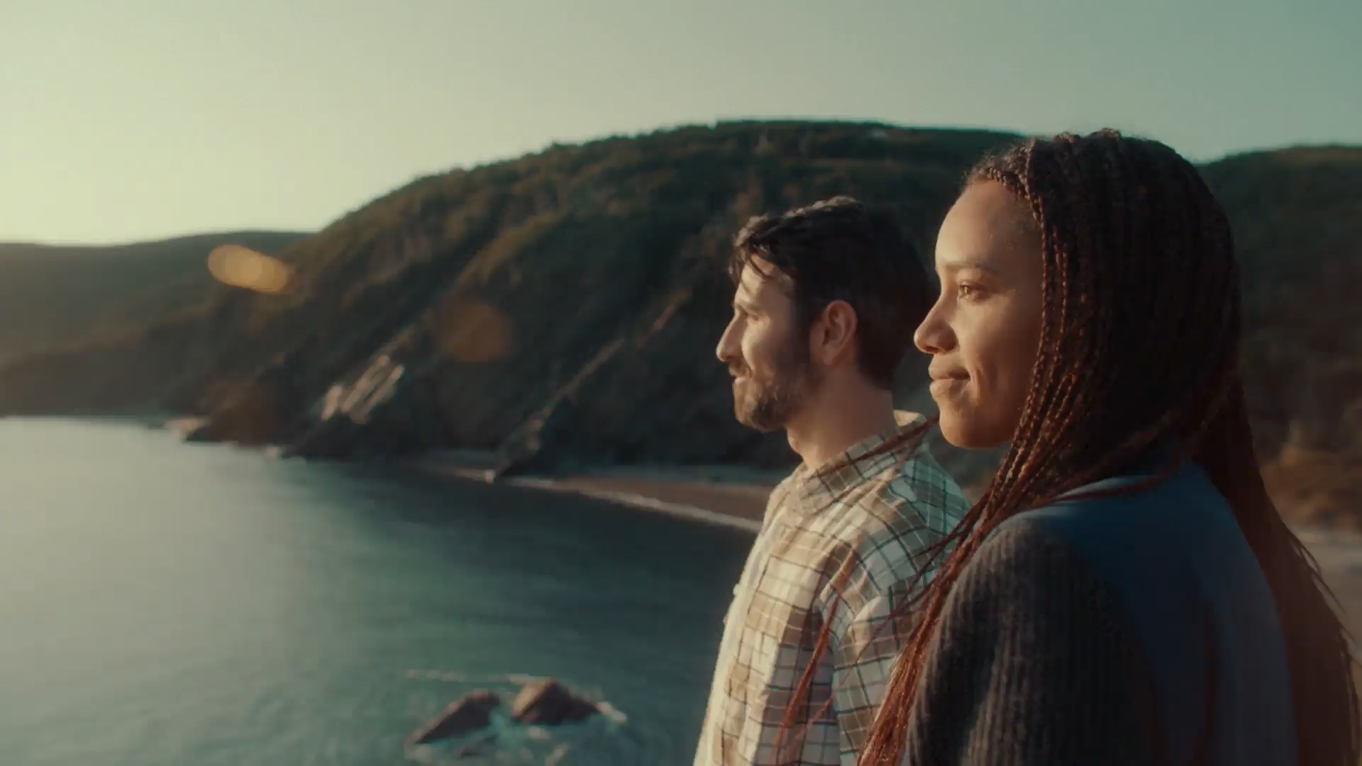 A man and woman stand on a cliff in Cape Breton, Nova Scotia