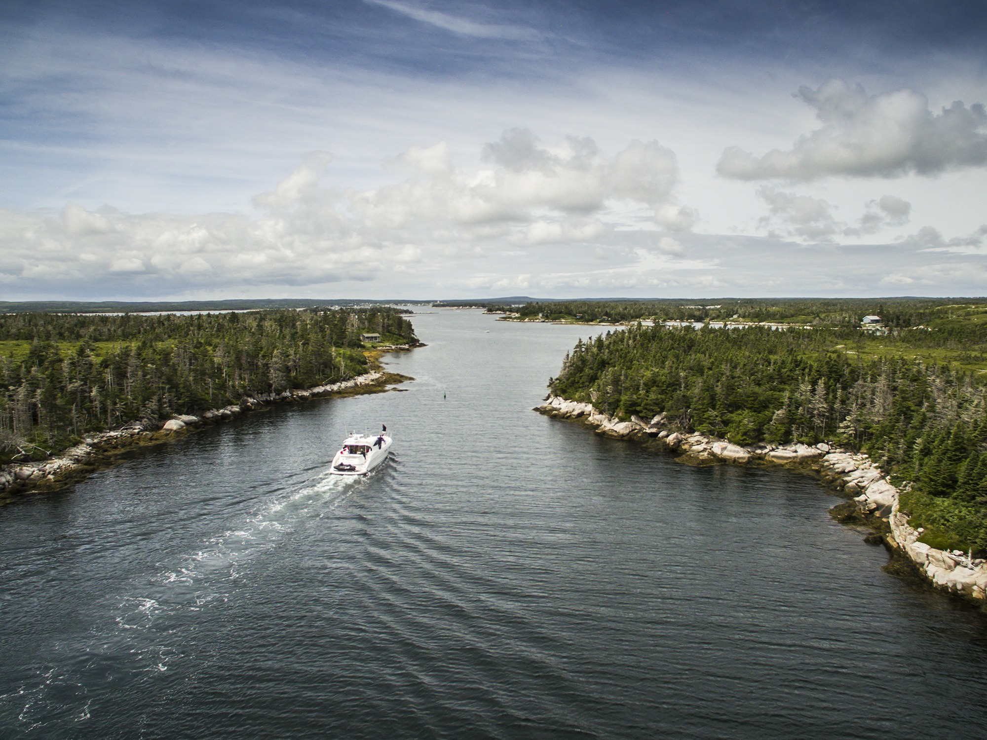 A yacht travels between an island and the shoreline of mainland Nova Scotia along Nova Scotia's Eastern Shore.