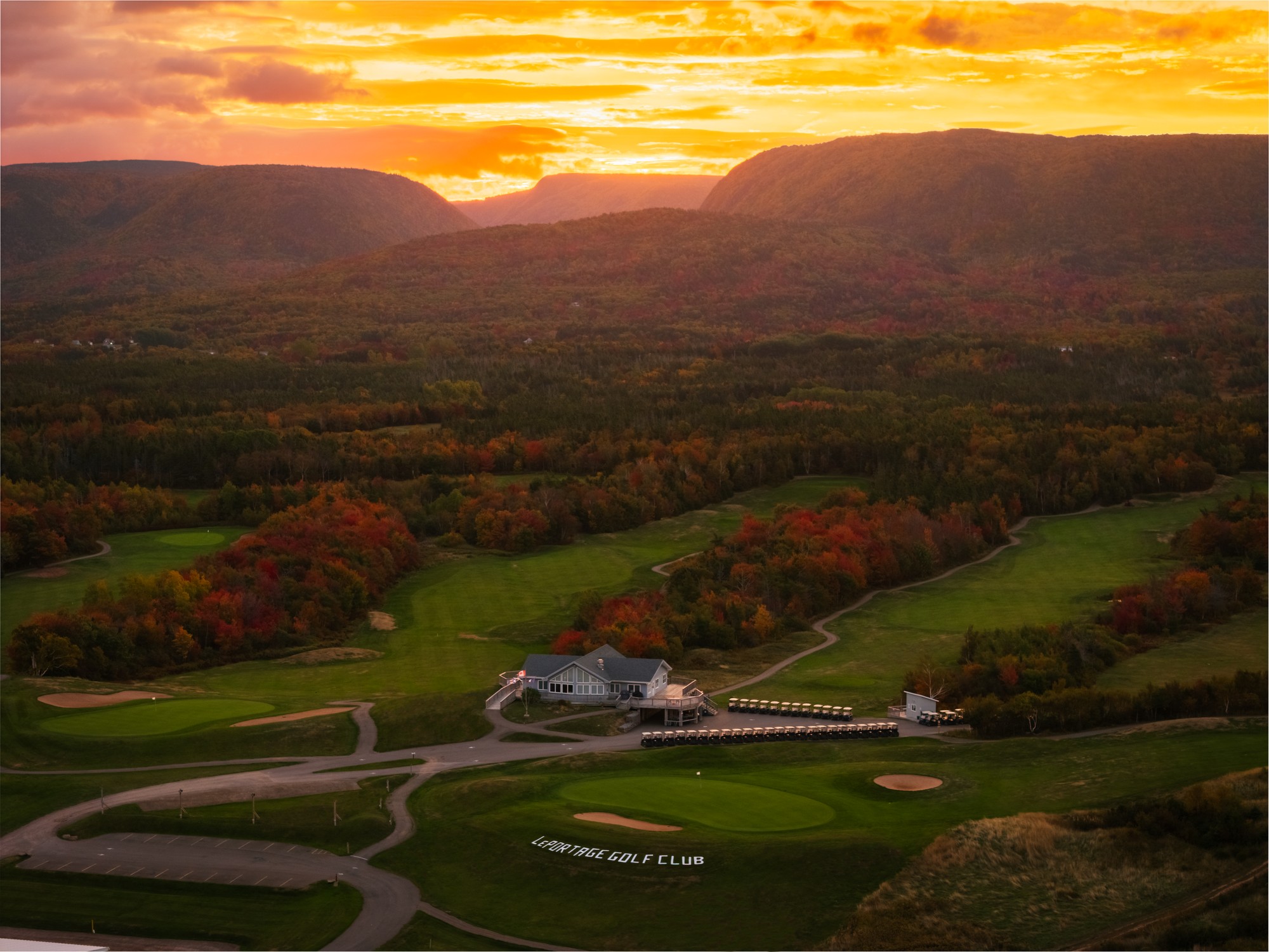 An aerial view of a golf course at sunset with fall colours in the highlands in the background in Cape Breton, Nova Scotia