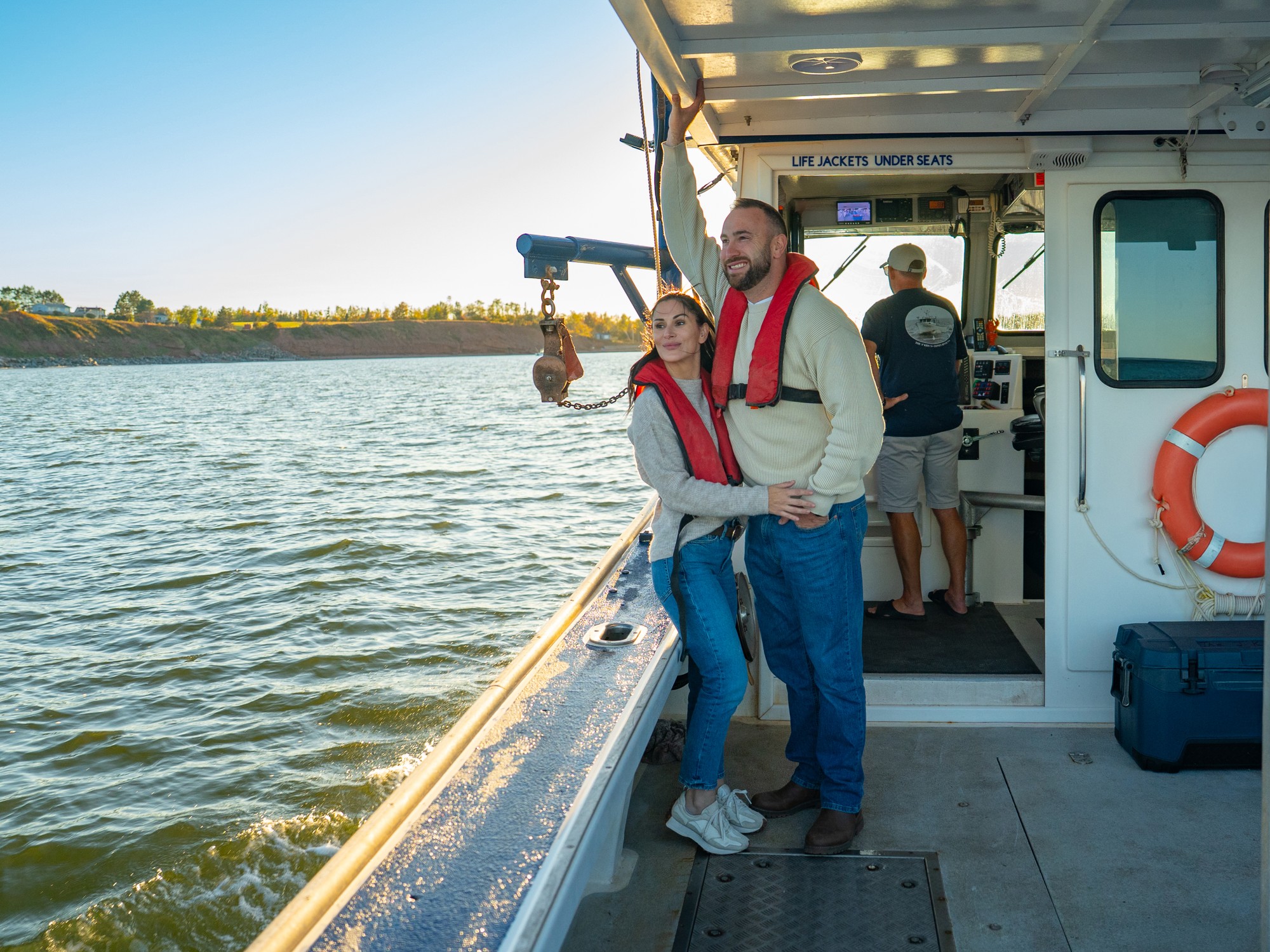 Two people stand on a fishing boat during a tour with Discover the Strait Boat tours near Pictou, Nova Scotia