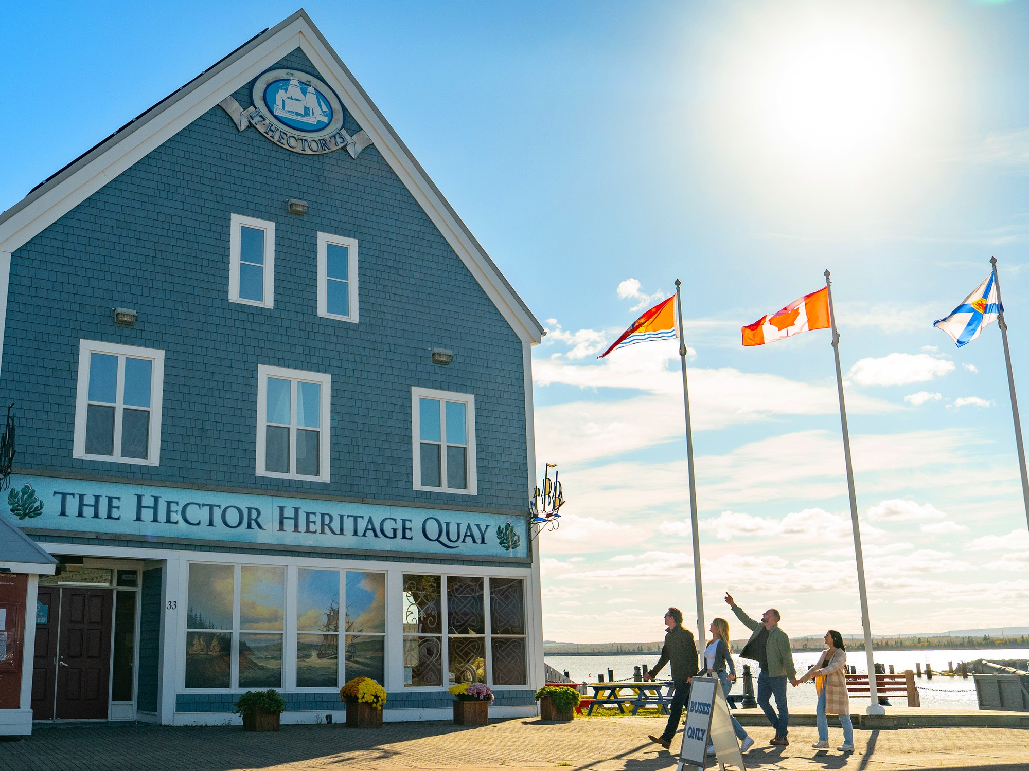 Four people walk past the exterior of the Hector Heritage Quay on the Pictou Waterfront in Nova Scotia.