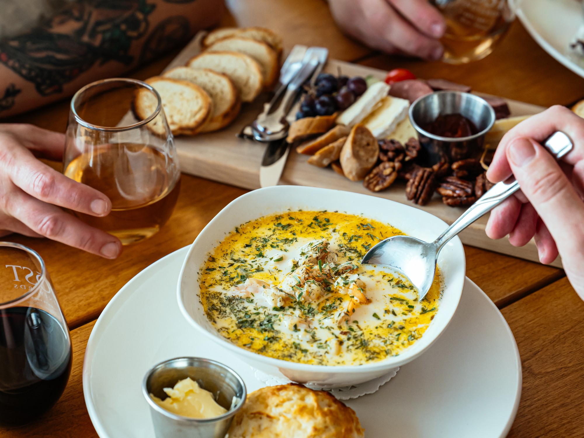 Chowder in a bowl with a biscuit on the site, charcuterie baord in the background at Jost Vineyards in Malagash, Nova Scotia