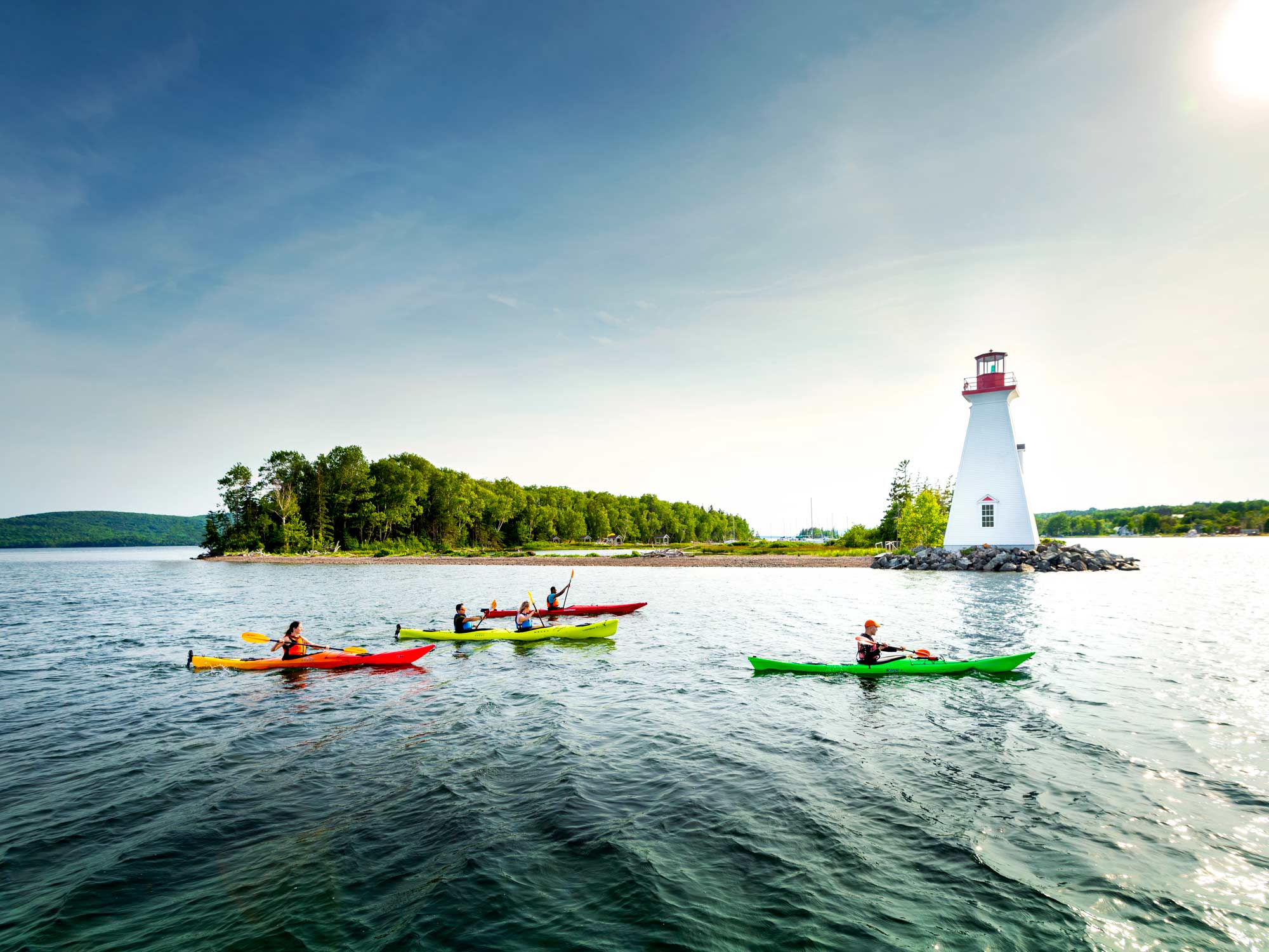 Kayakers paddling in Baddeck Bay near Kidston Island and the Kidston Island Lighthouse on a sunny summer day in Baddeck, Cape Breton, Nova Scotia