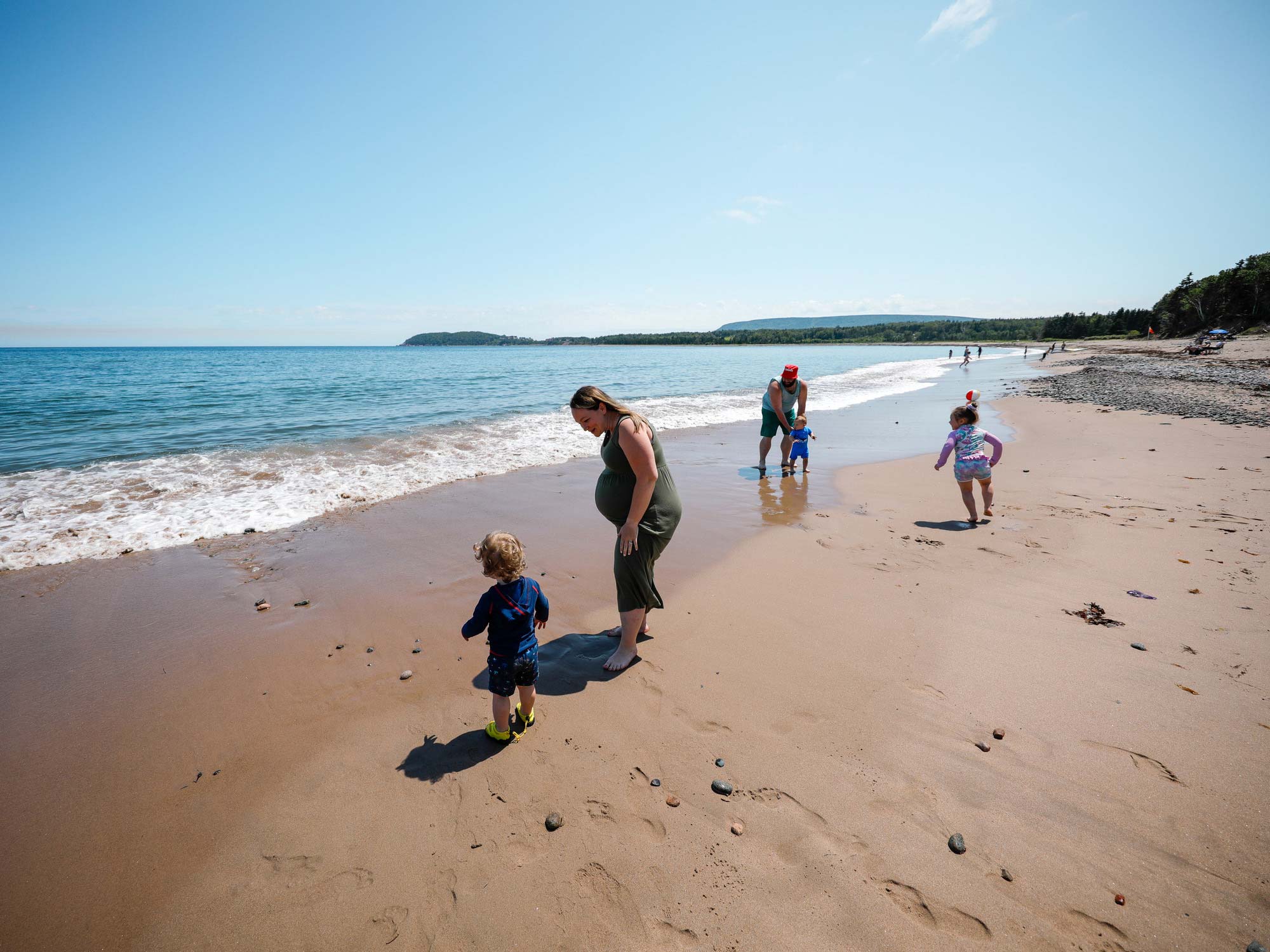 Family playing on the sandy shoreline of North Bay Beach in Ingonish within the Cape Breton Highlands National Park in Nova Scotia.