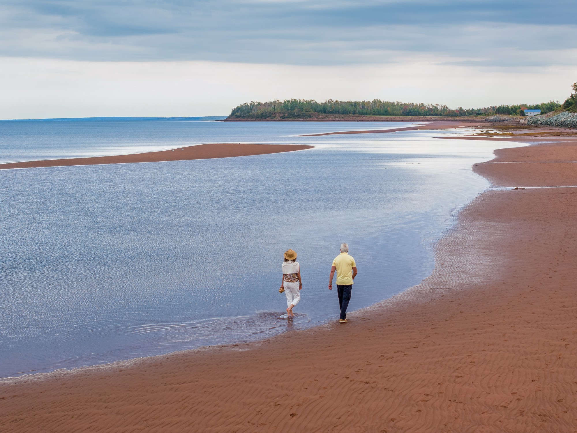 Two people walk along the sand flats at Northport Beach in Nova Scotia
