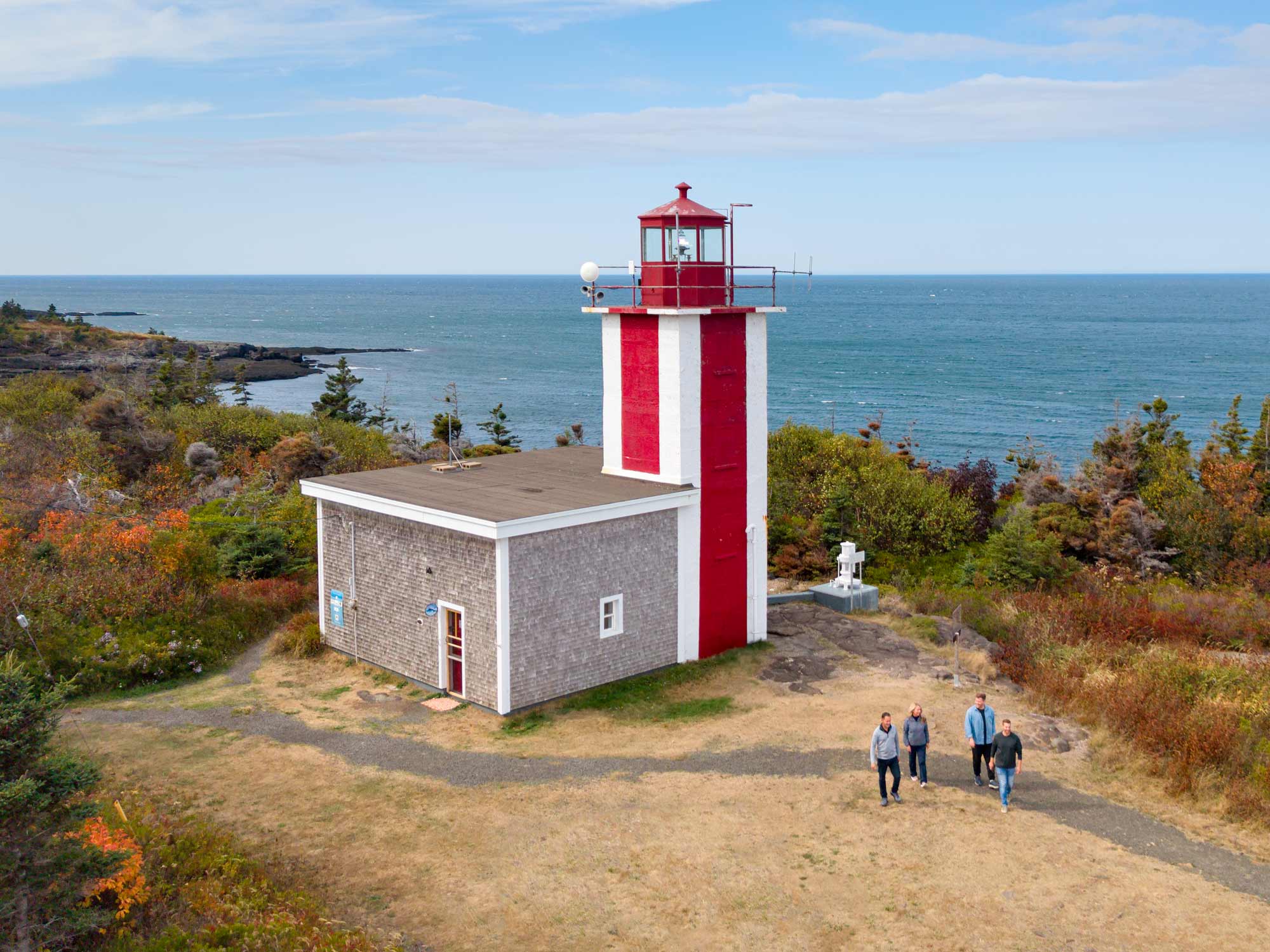 Four people walking on the grounds of Point Prim Lighthouse near Digby, Nova Scotia on the Bay of Fundy in Fall.