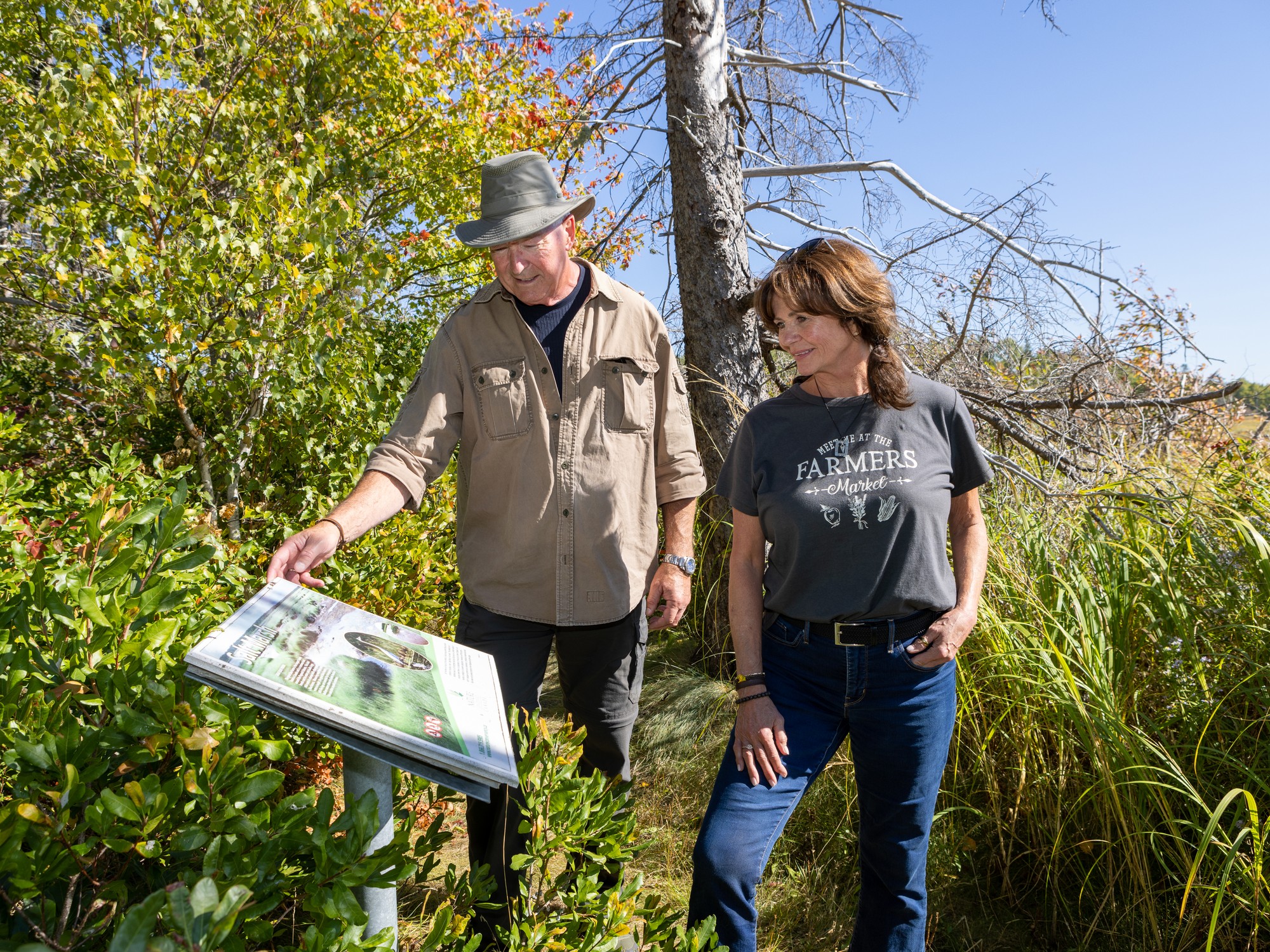 Two people look at a plaque along the Pugwash Estuary Trail in Nova Scotia.
