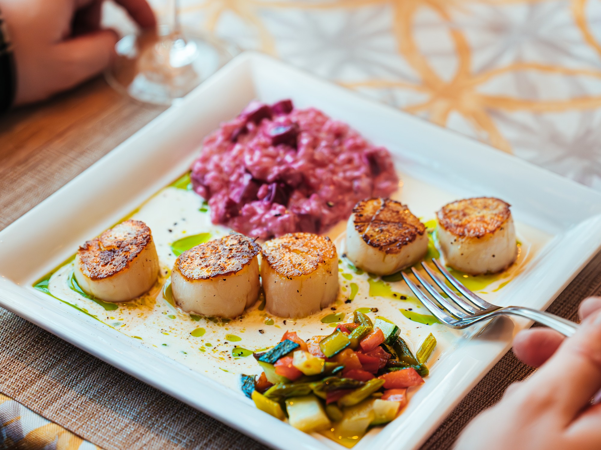 A diner is about to stick a fork into a plate of scallops at Wiley's by the Wharf in Wallace, Nova Scotia