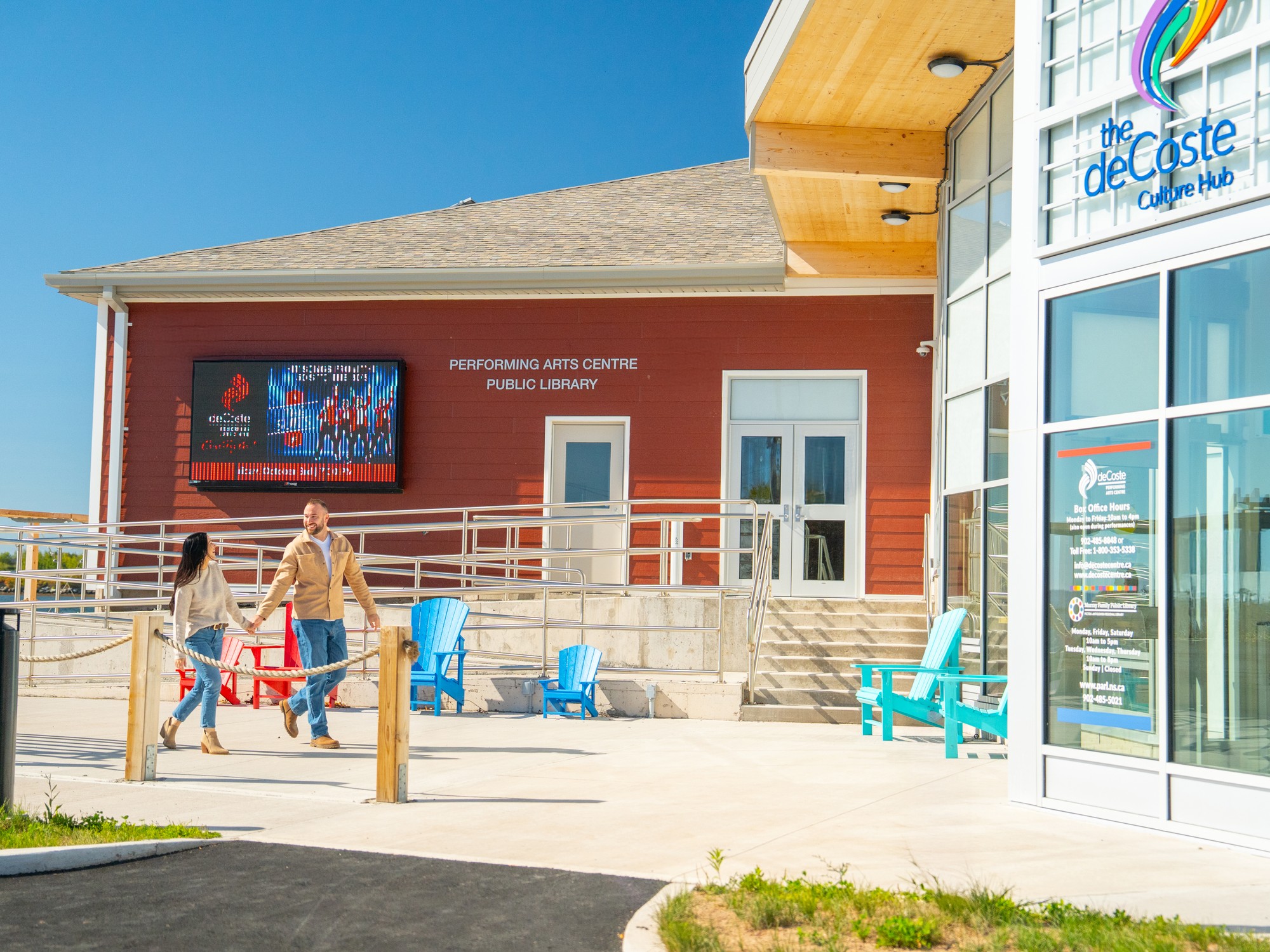 Two people walk in front of the deCoste Performing Arts Centre in Pictou, Nova Scotia