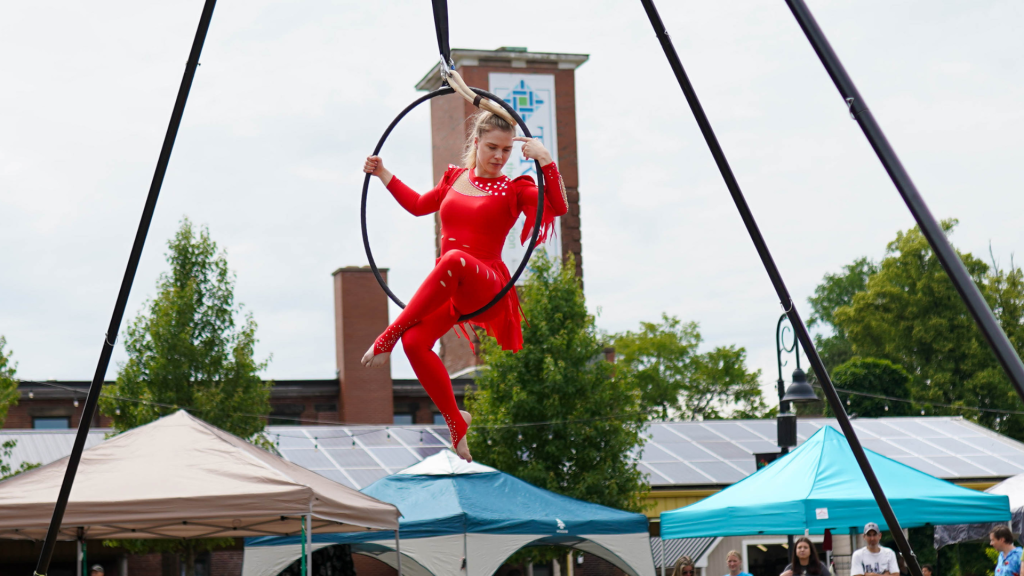 A performer in a red unitard swings in a hula hoop at the Truro Buskerfest in Nova Scotia