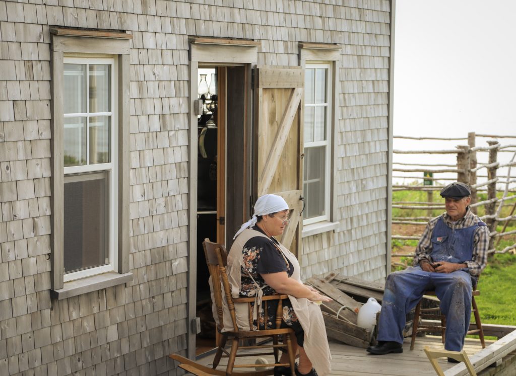 A person sits outside a building during the Acadian Evenings at the Interpretation House at Mkwesaqtuk/Cap-Rouge Campground in Cape Breton, Nova Scotia
