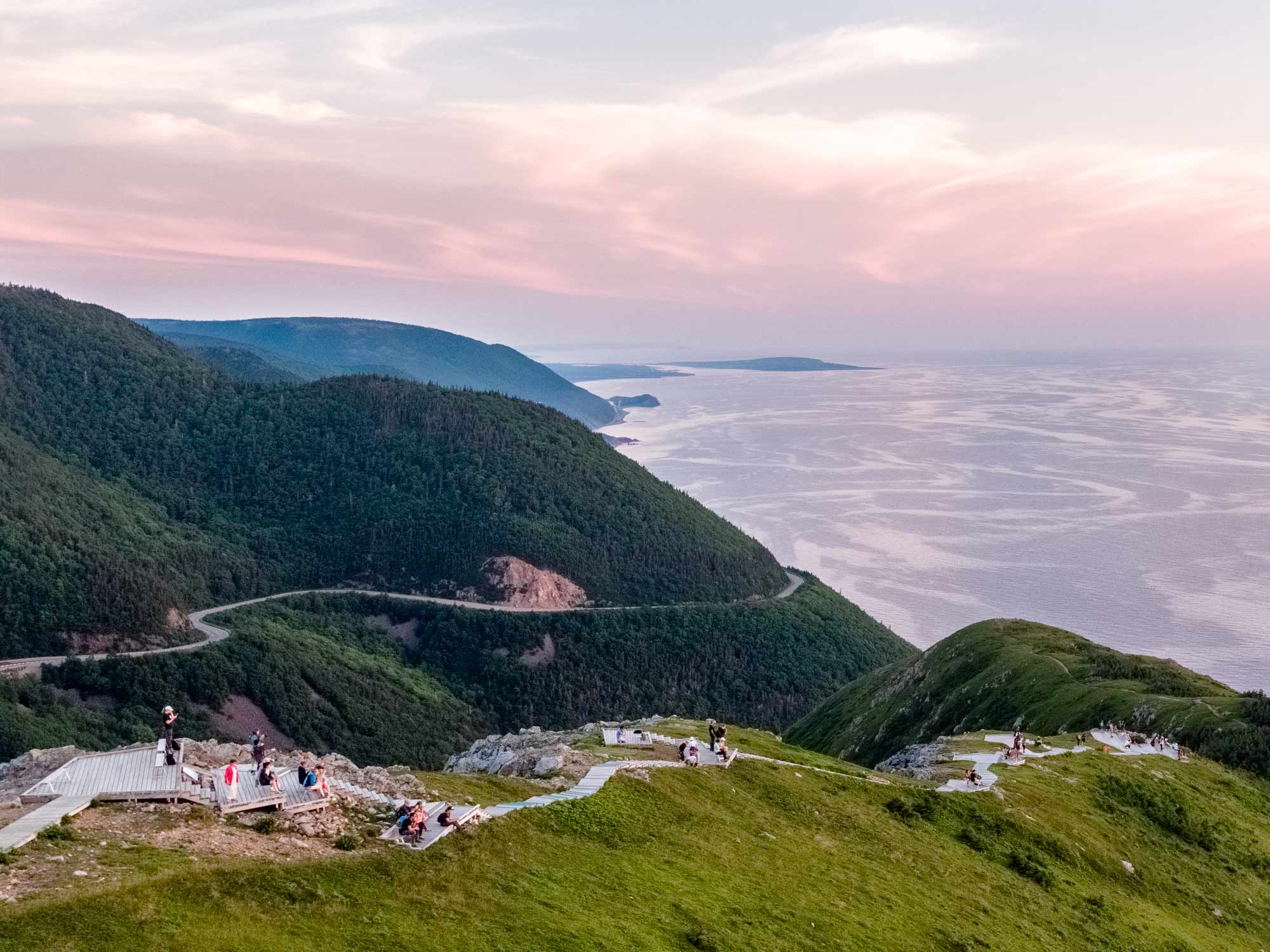 A drone aerial view over the entire Skyline Trail headland boardwalk just after sunset with the Cabot Trail in the distance in the Cape Breton Highlands National Park in Nova Scotia.