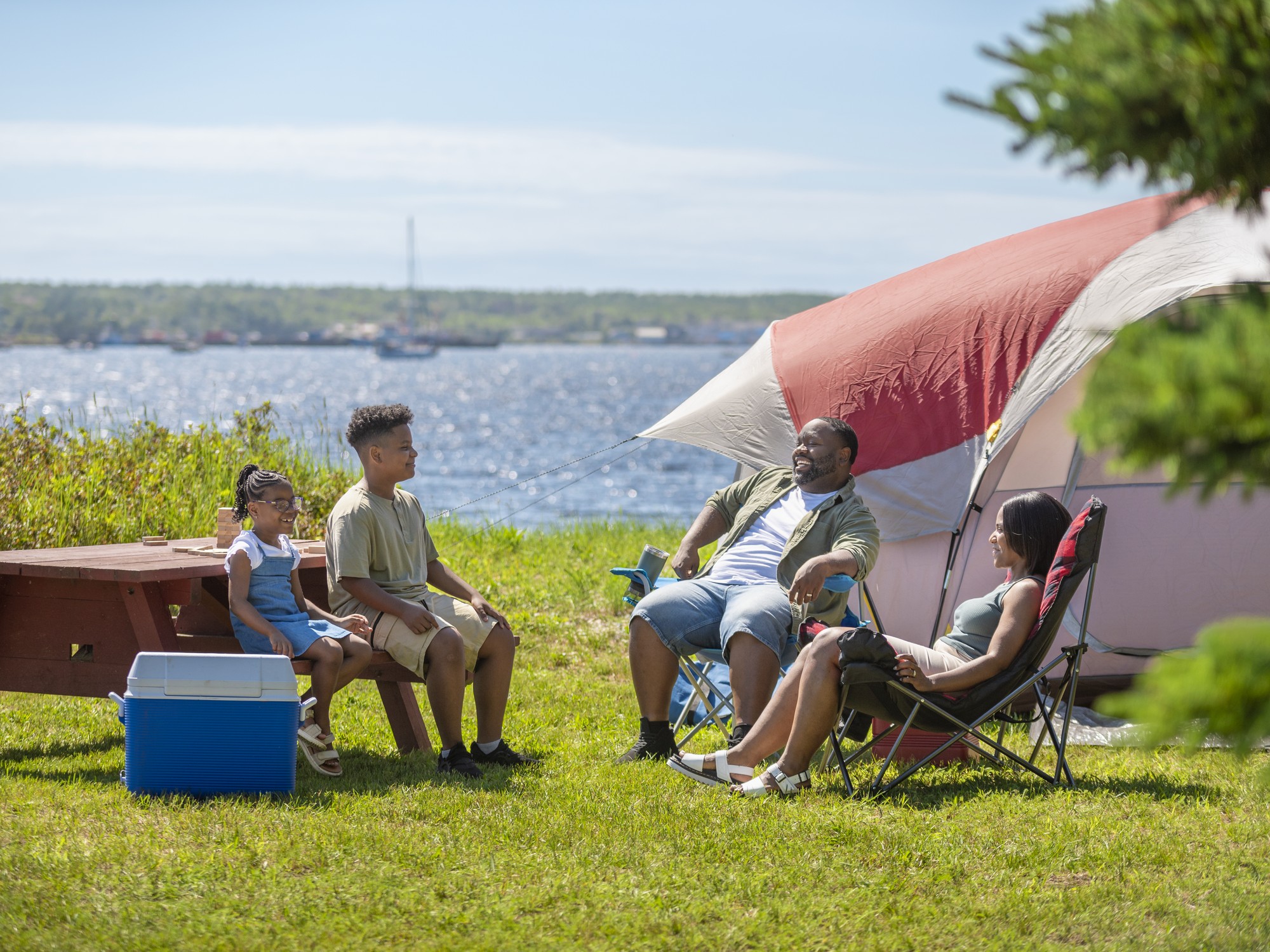 A family relaxes ouside of their tent while camping at the Islands Provincial Park near Shelburne, Nova Scotia