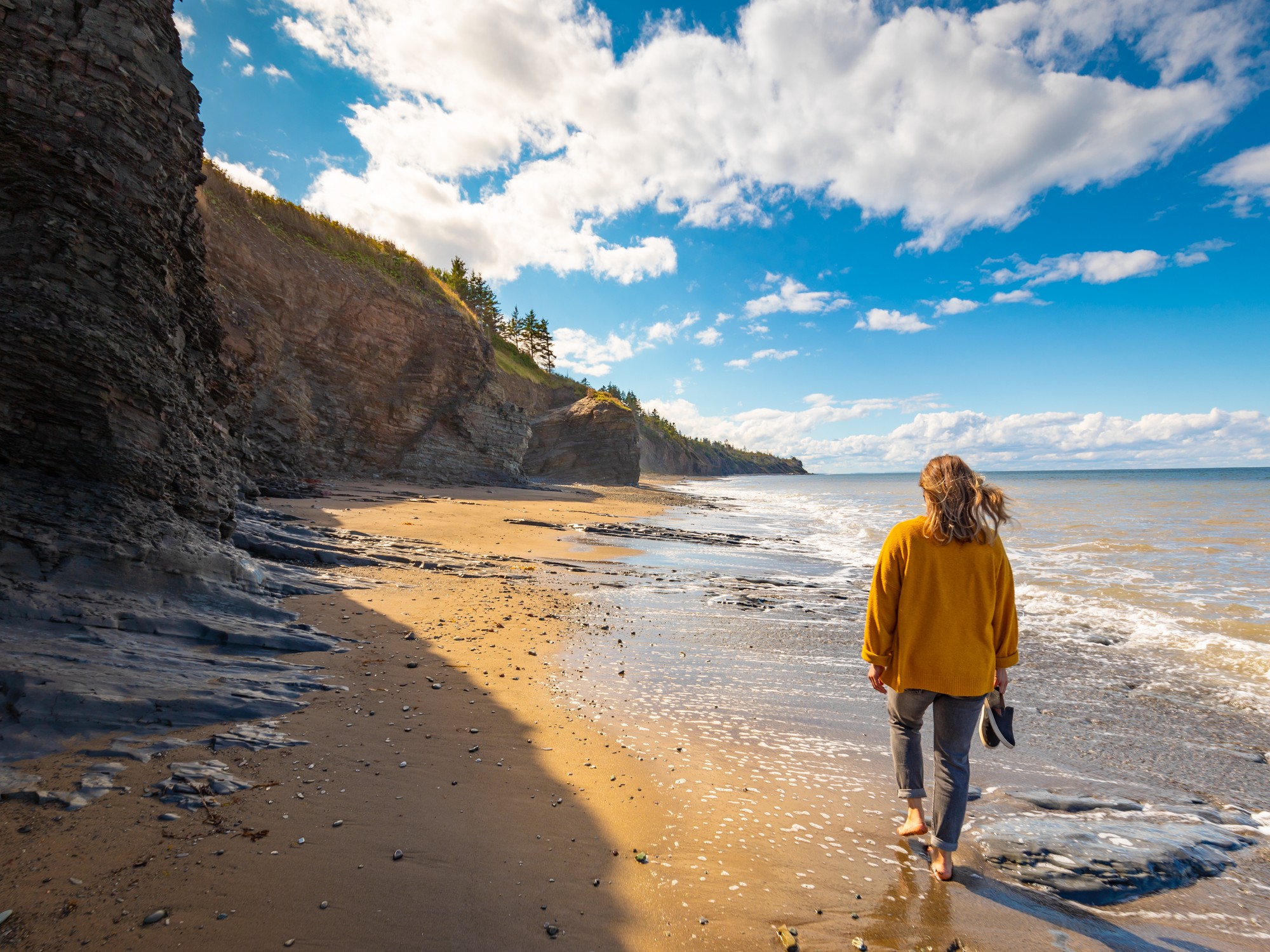 A woman walks on the beach at Arisaig Provincial Park in Nova Scotia.